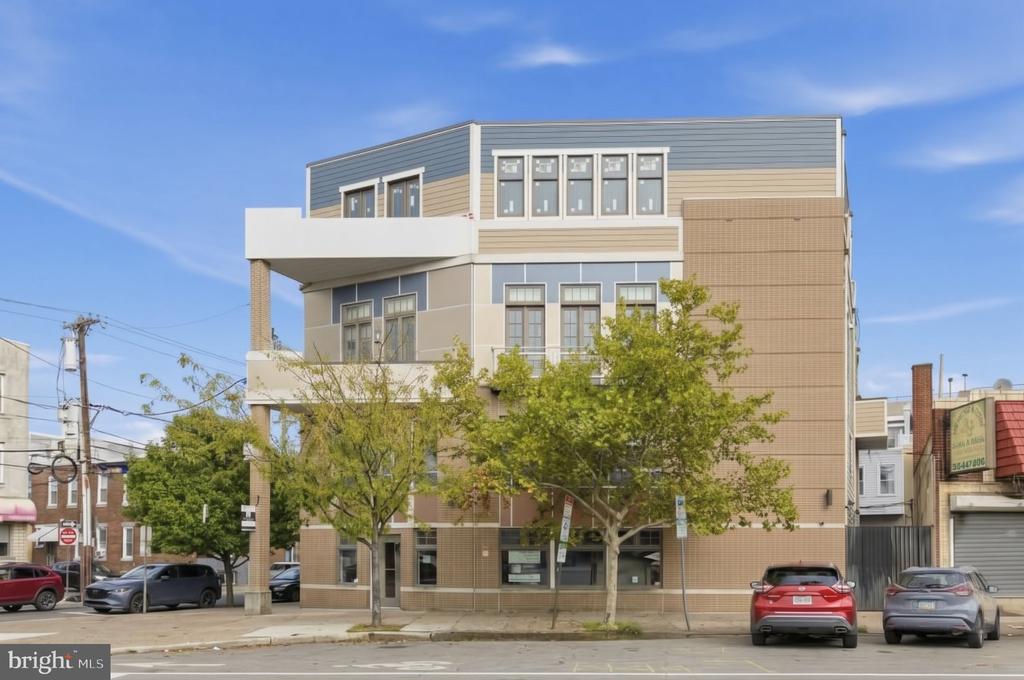 Modern multistory brick building with balconies and street-level storefronts.