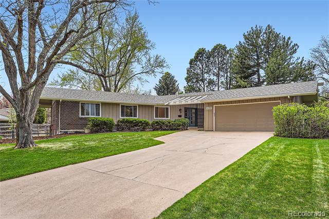 Single-story brick ranch home with an attached garage, wide driveway, and mature trees.