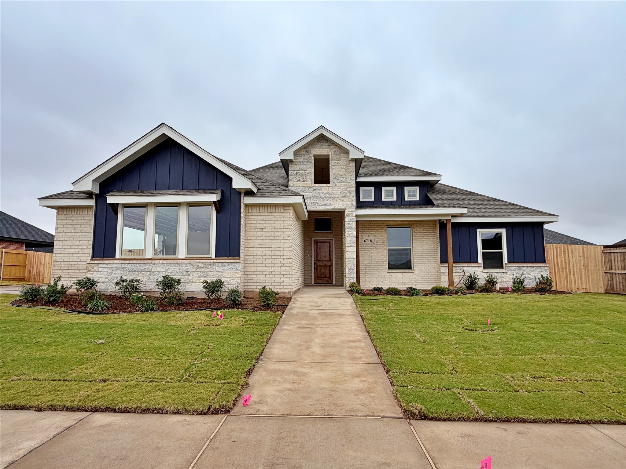 House exterior with cream brick, stone, navy siding, and a walkway across the front lawn.