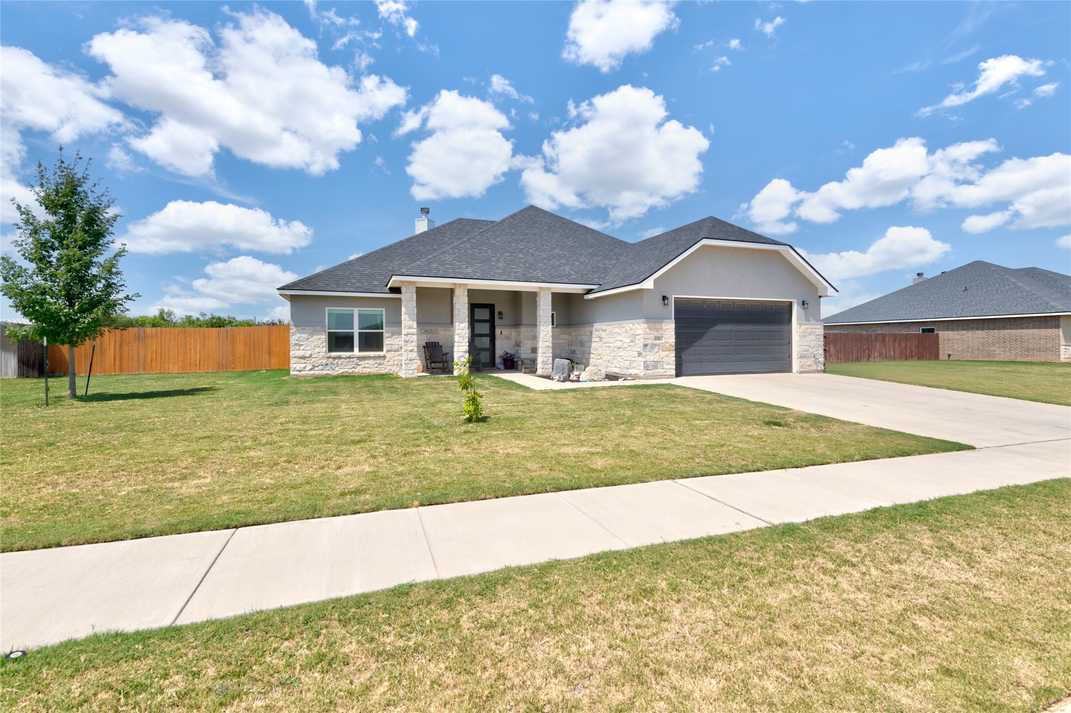 Gray single-story home with stone accents, a covered porch, and an attached garage.