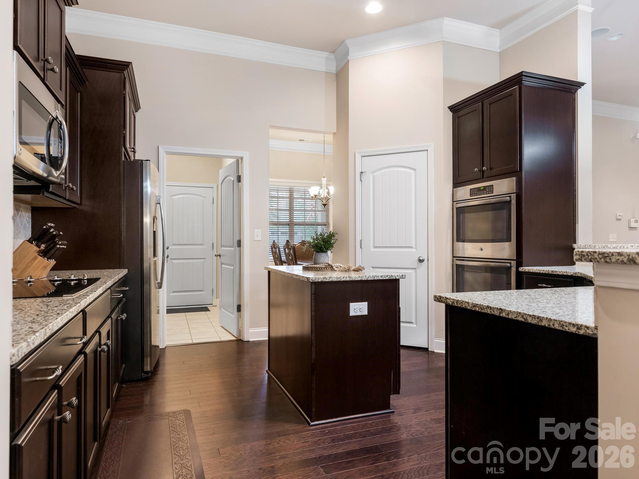 Kitchen with dark wood cabinetry, granite counters, stainless steel appliances, and a central island.