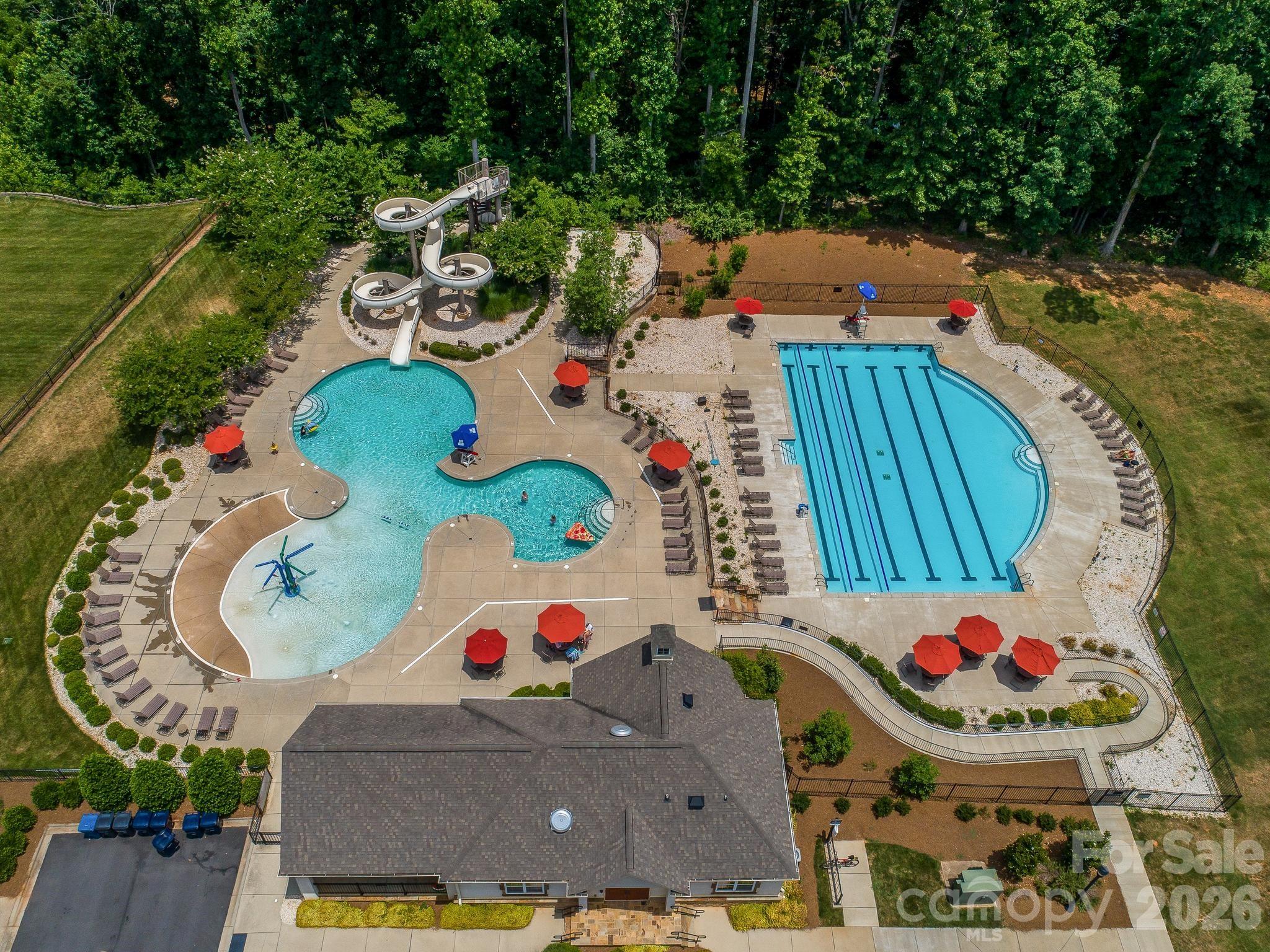 Aerial view of a community pool complex with a twisting waterslide and separate lap pool.