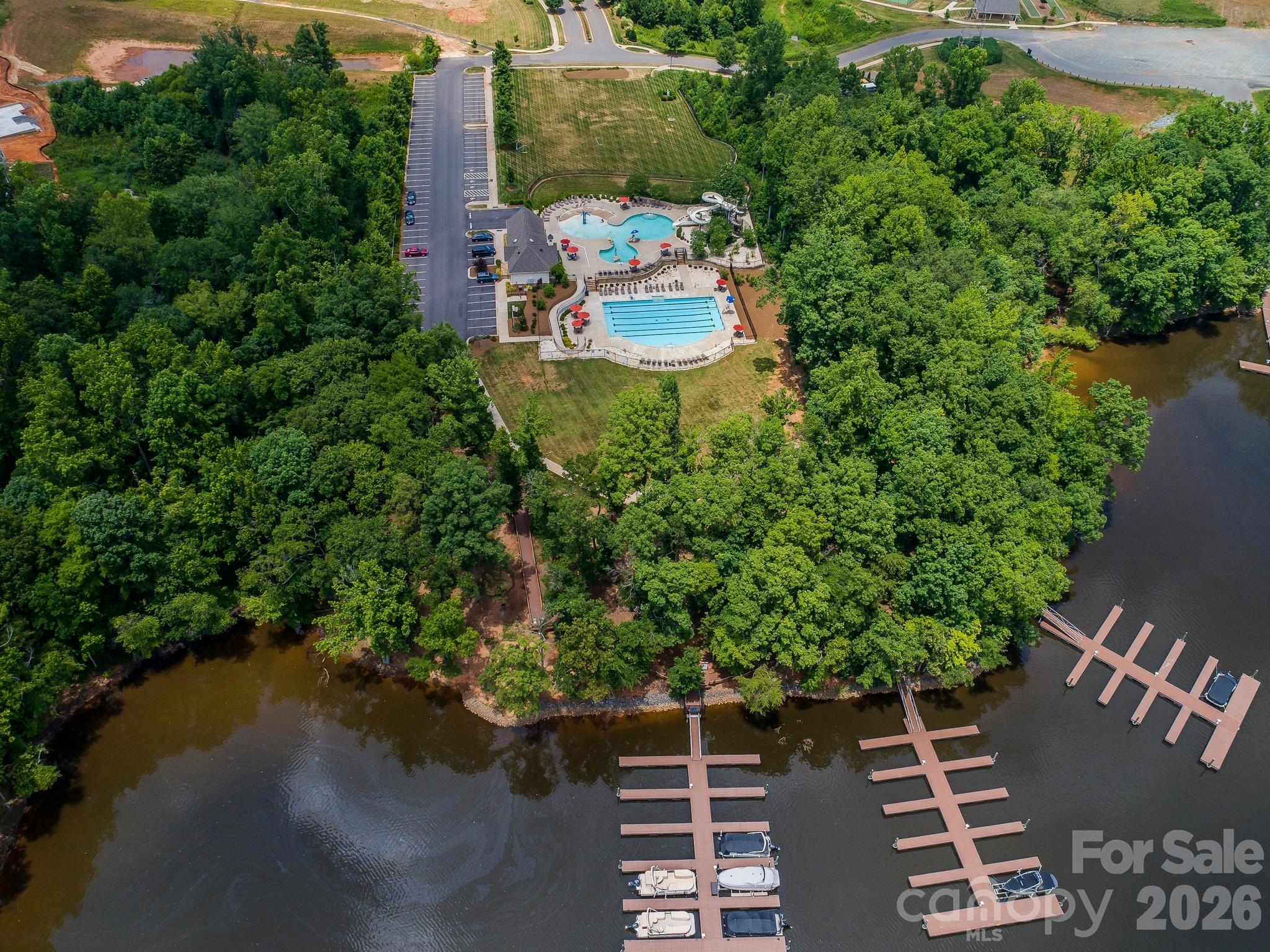 Aerial view of waterfront community with swimming pools, wooded shoreline, and boat docks.