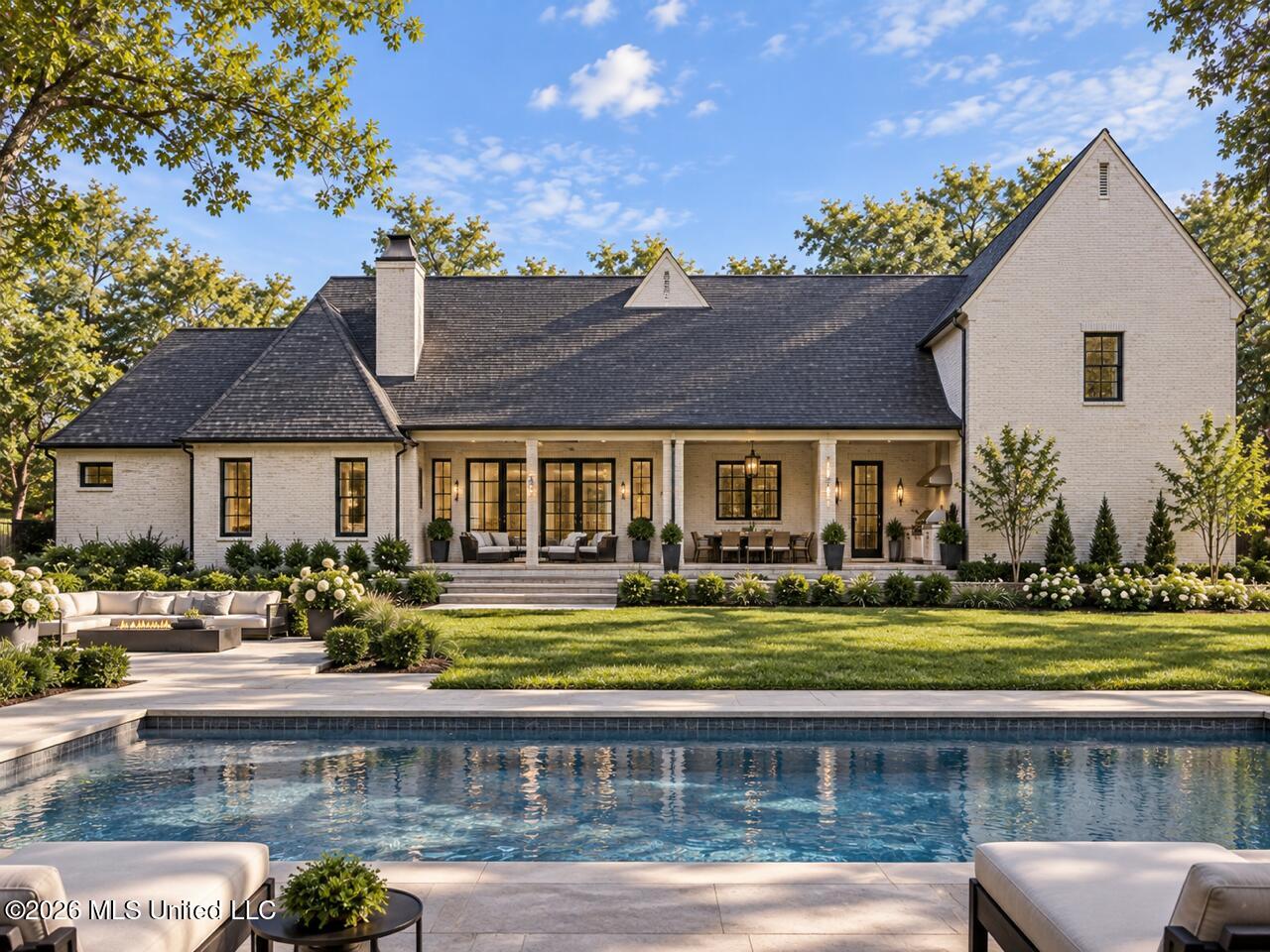 White-brick house with a covered patio, landscaped lawn, and swimming pool in the foreground.