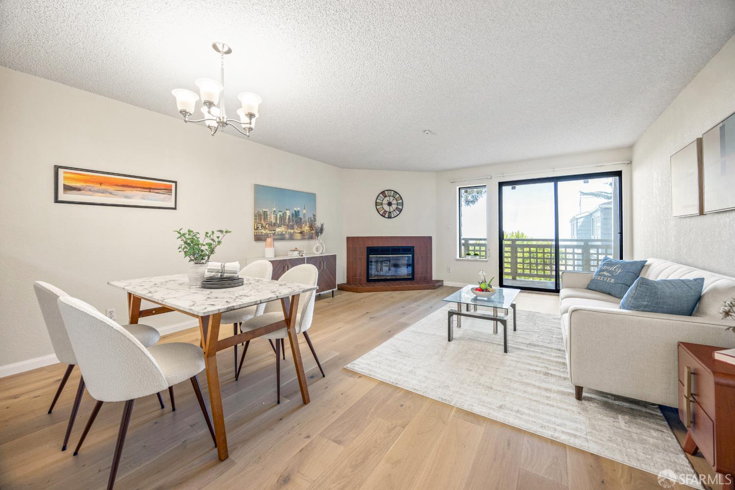 Staged living and dining room with a tiled fireplace and sliding doors opening to a balcony.