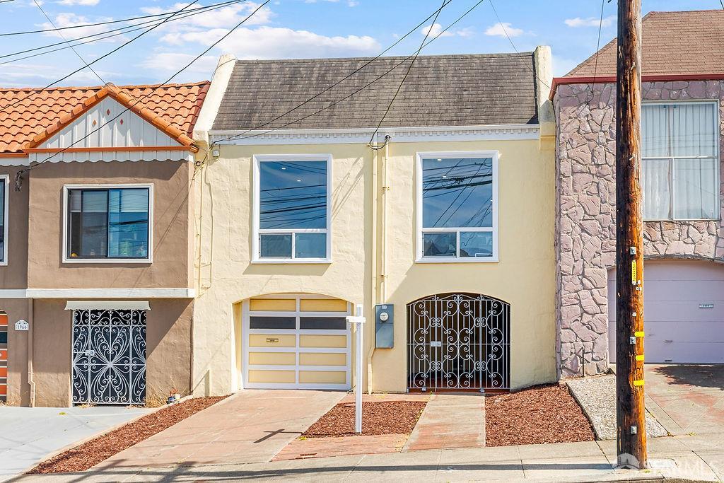 San Francisco home with a pale yellow facade, driveway garage, and decorative iron entry gate.