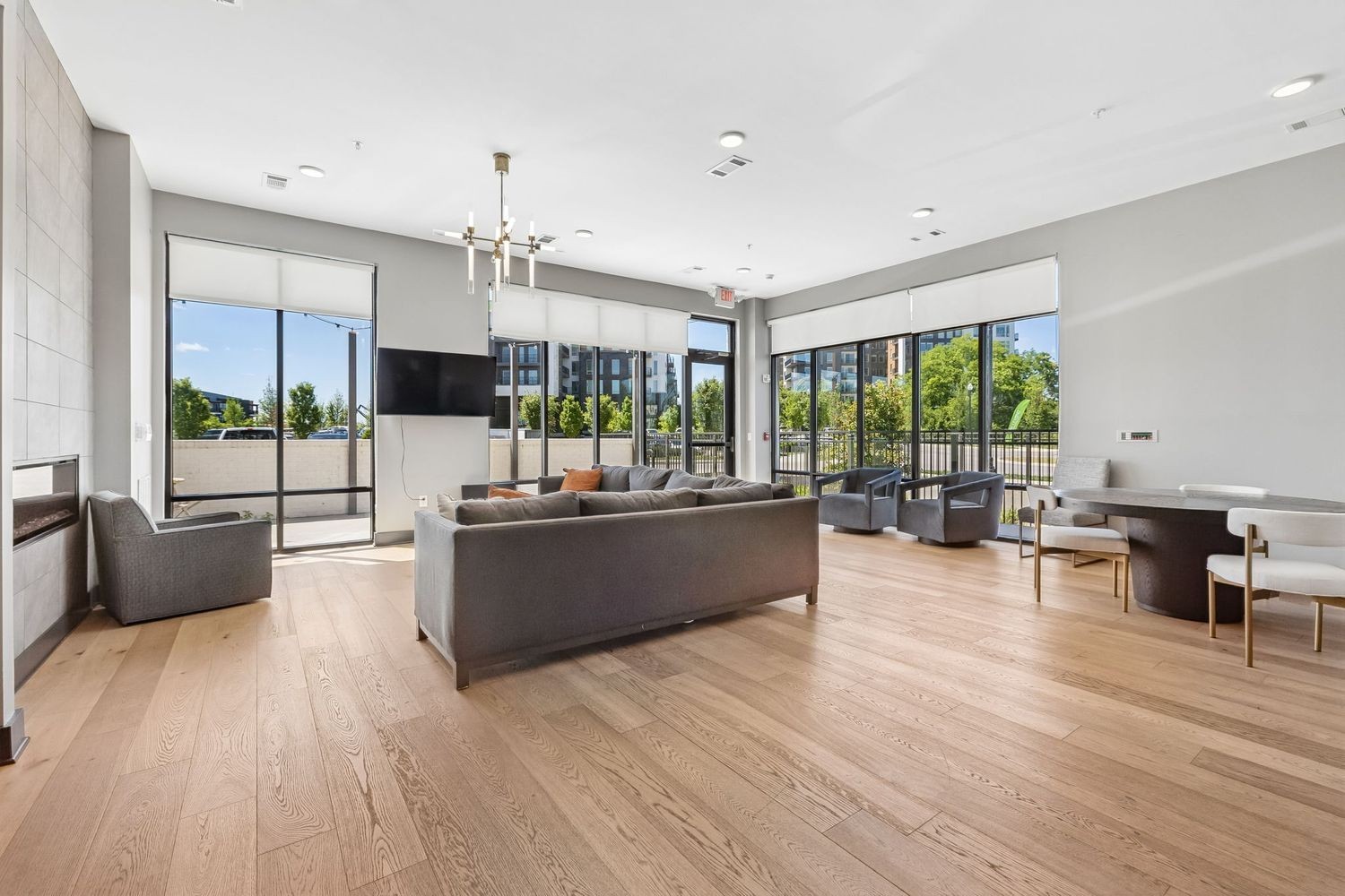 Furnished apartment lounge with a gray sectional, fireplace, and large windows opening onto a terrace.