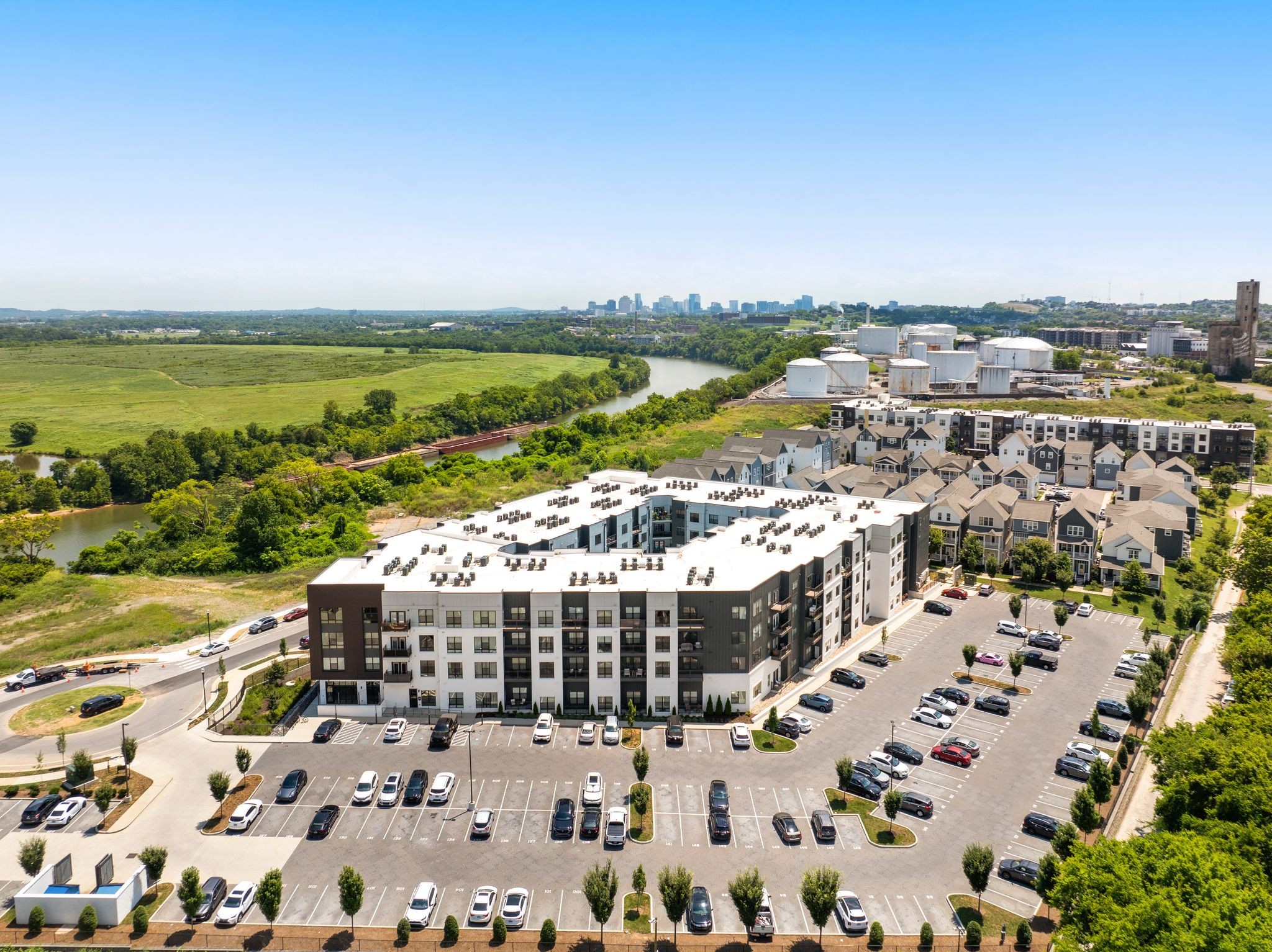 Aerial view of an apartment complex beside a river, with the Nashville skyline in the distance.