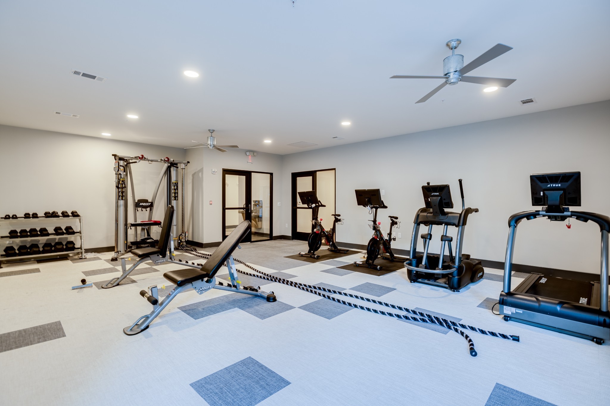 Fitness room with treadmills, stationary bikes, weight equipment, and exercise ropes.