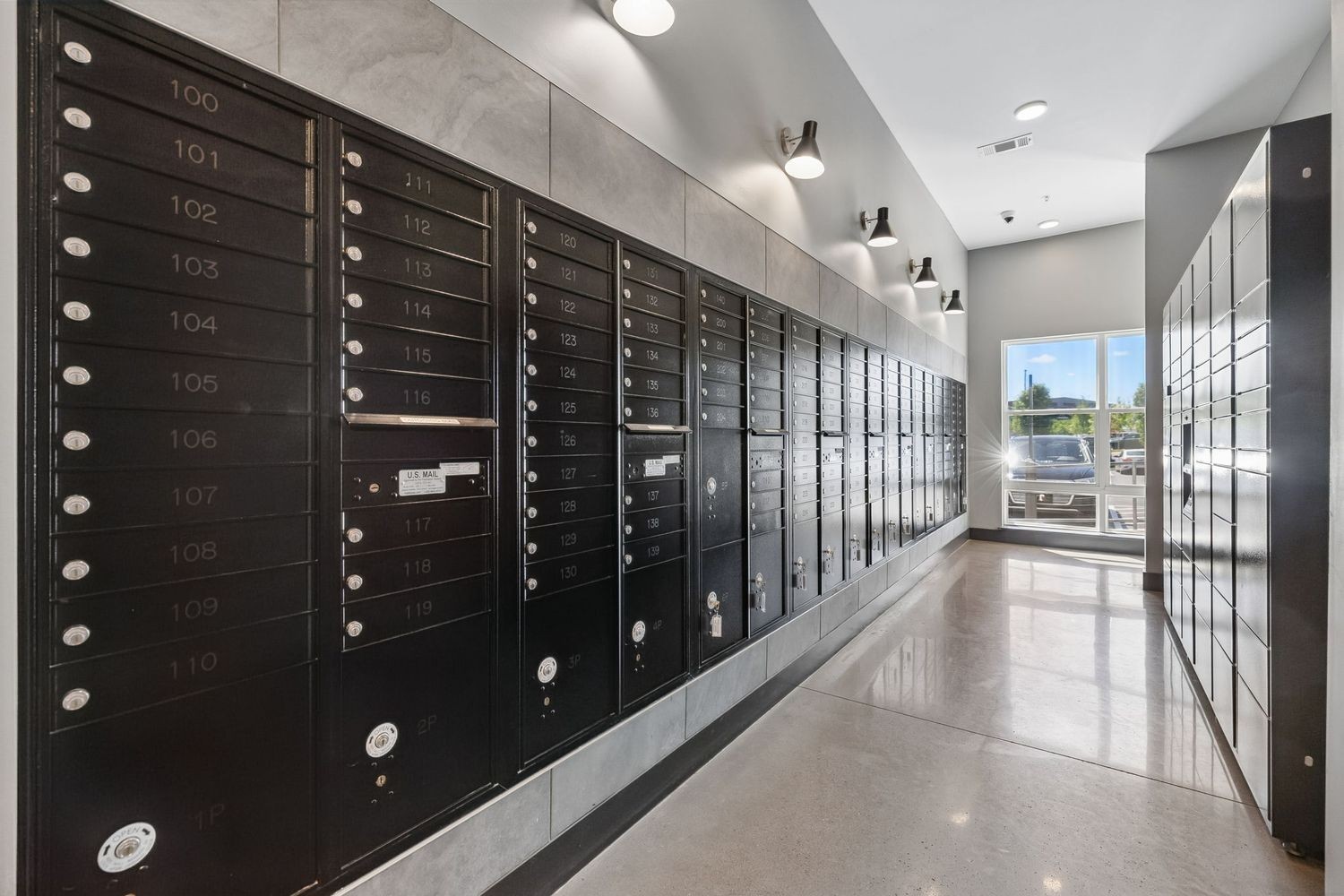 Apartment mailroom with rows of black mailboxes and a polished floor.