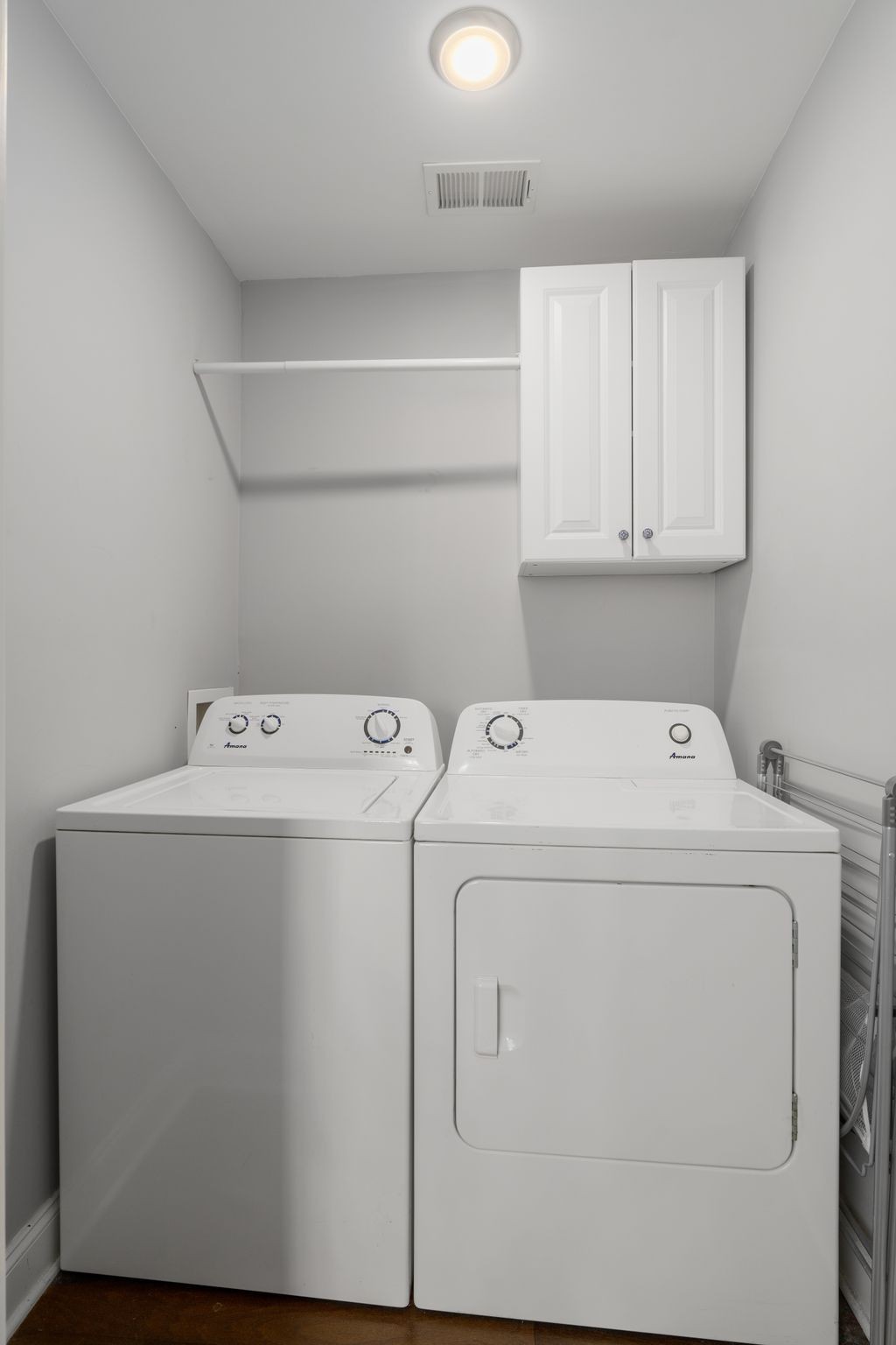 Laundry room with a washer and dryer beneath white wall cabinets.