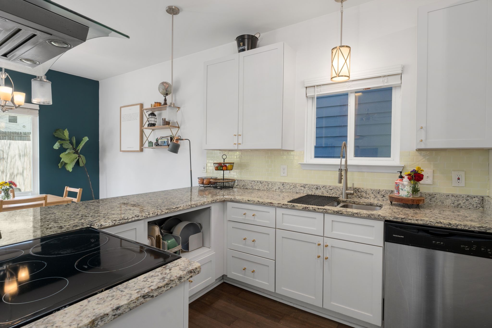 Kitchen with white cabinets, granite counters, pale yellow tile backsplash, and a black cooktop.
