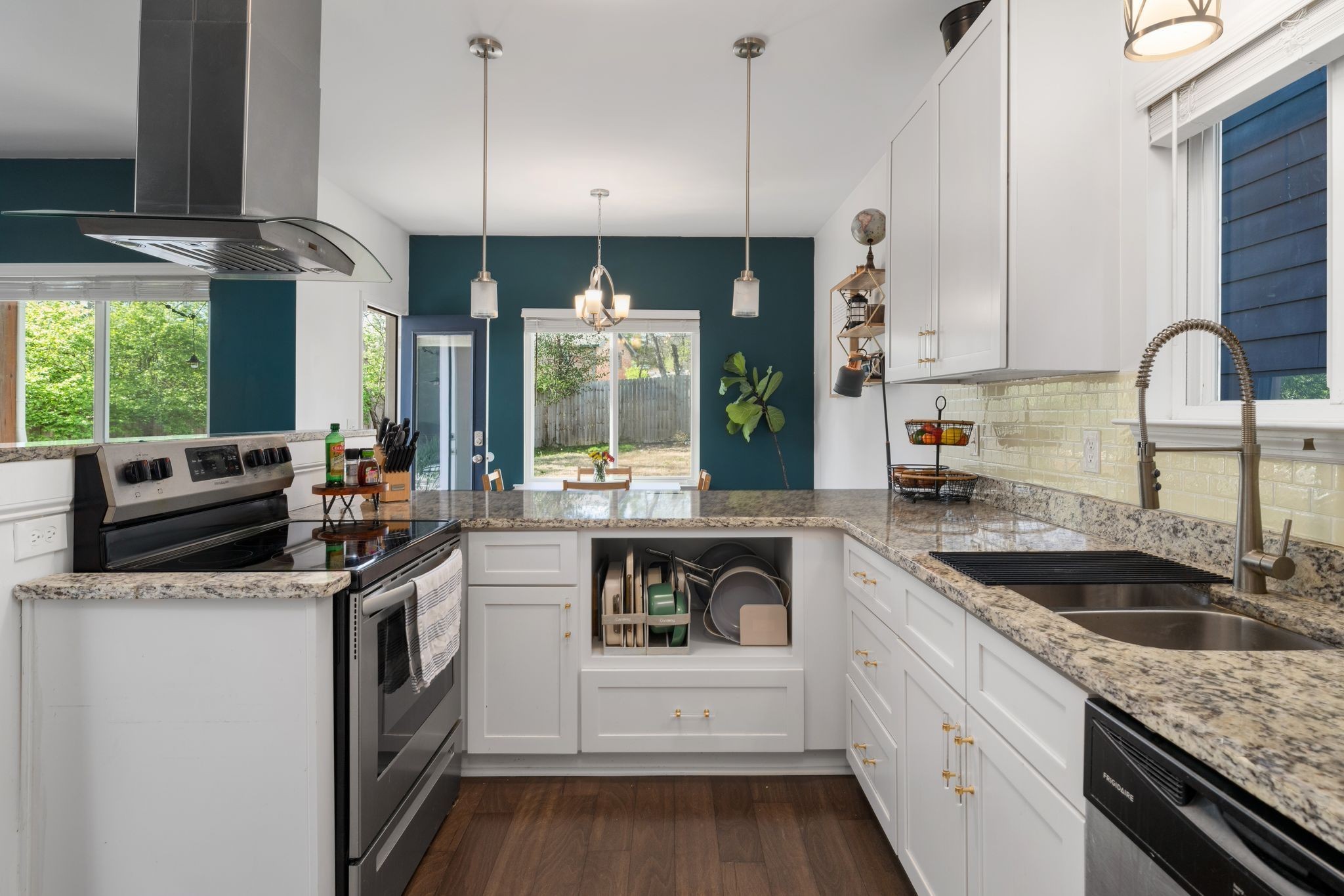 Bright kitchen with white cabinets, granite counters, stainless steel appliances, and a dark teal accent wall.