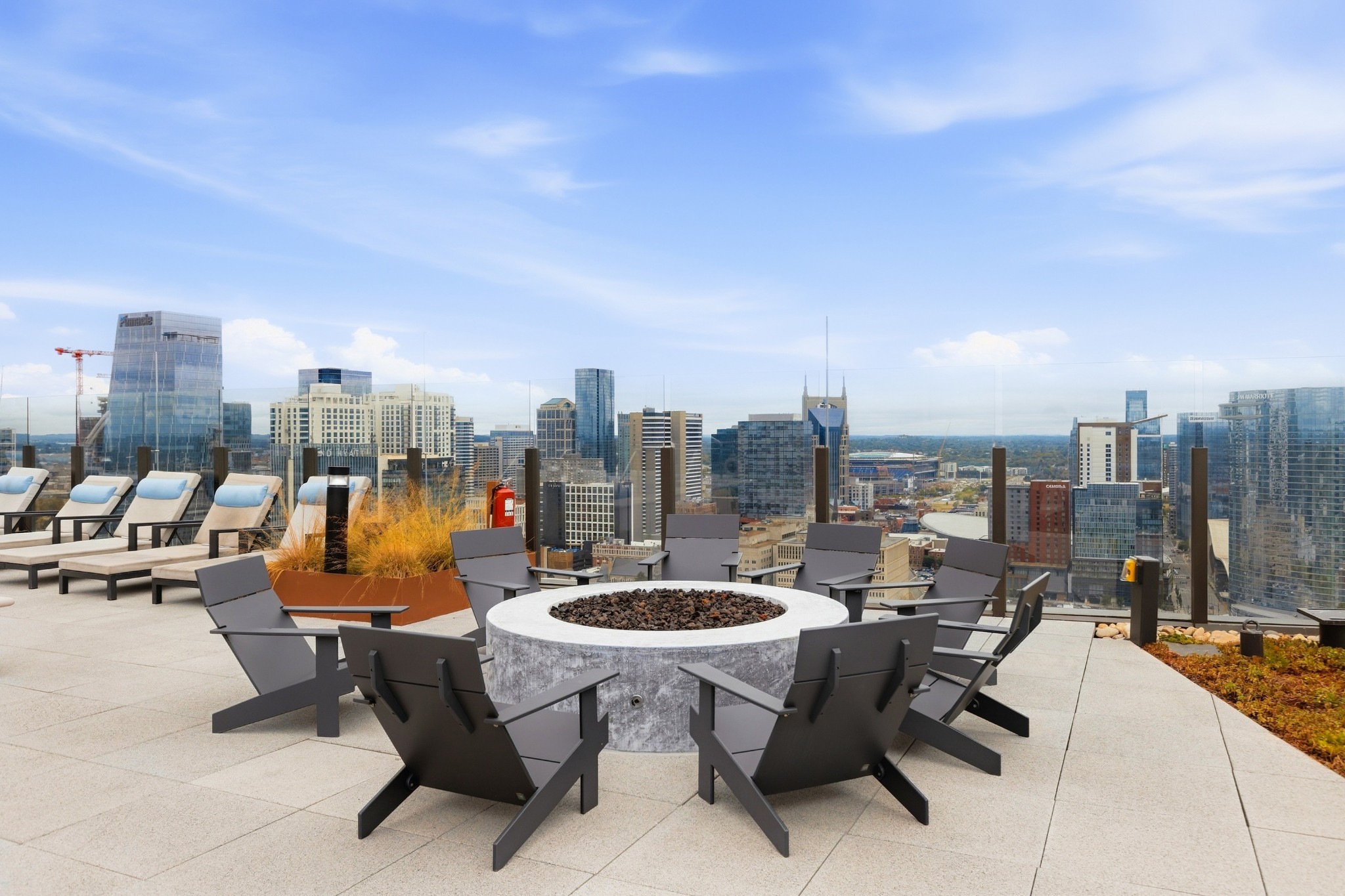 Rooftop terrace with lounge chairs around a circular fire pit and views of the Nashville skyline.