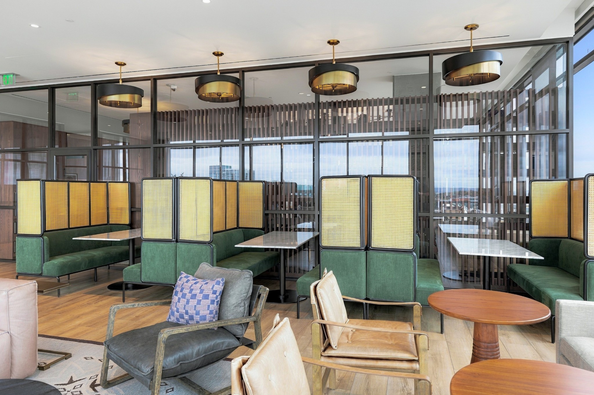 Building lounge with green booth seating, marble tables, and floor-to-ceiling windows overlooking the city.