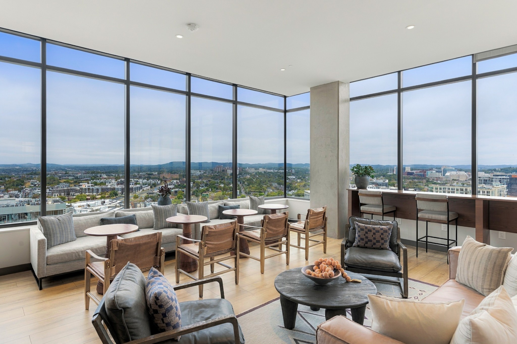 Furnished lounge with floor-to-ceiling windows overlooking the city skyline.