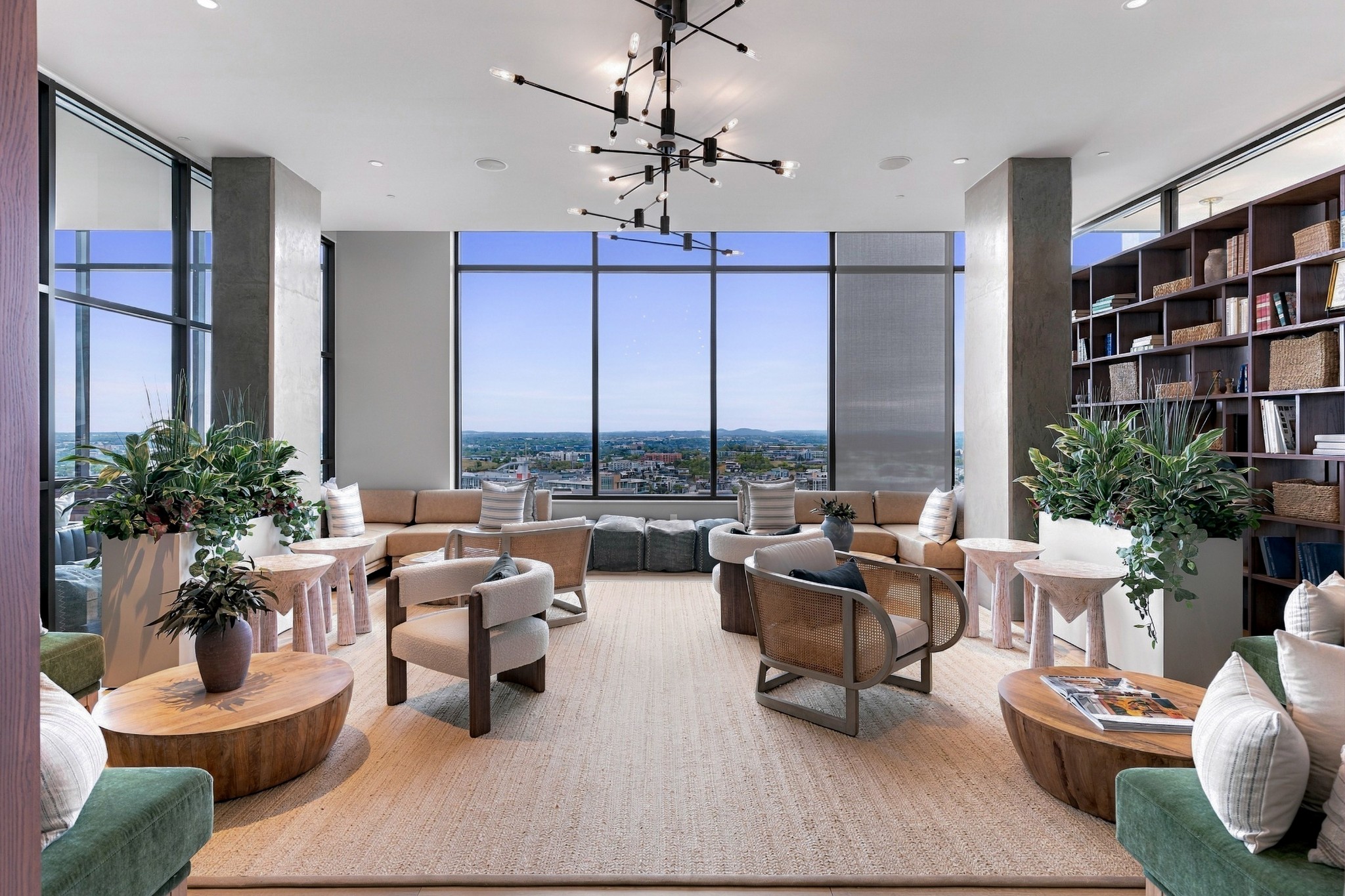 Furnished high-rise lounge with floor-to-ceiling windows overlooking the city and built-in bookshelves.