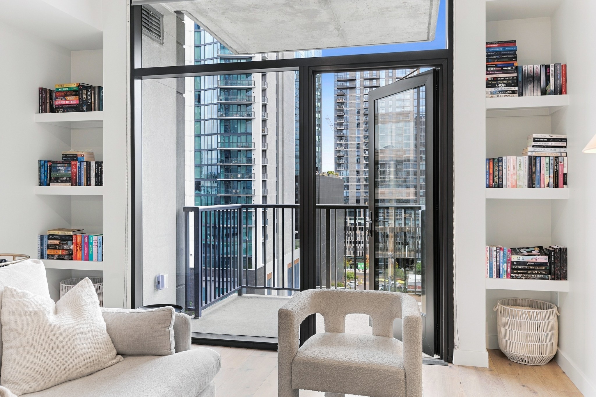 Condo living room with built-in bookshelves, balcony doors, and views of downtown high-rises.