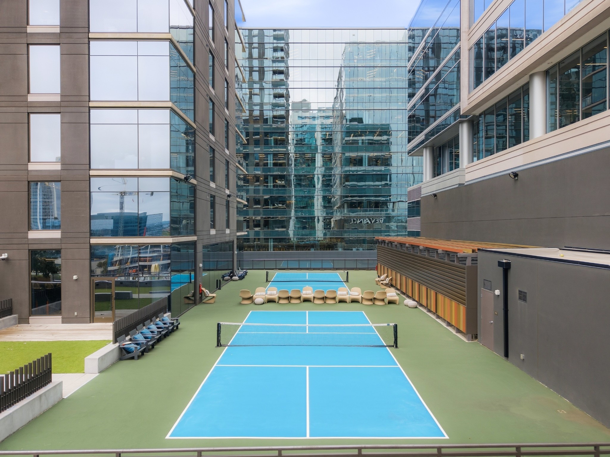 Pickleball courts and seating in a courtyard surrounded by modern apartment buildings.