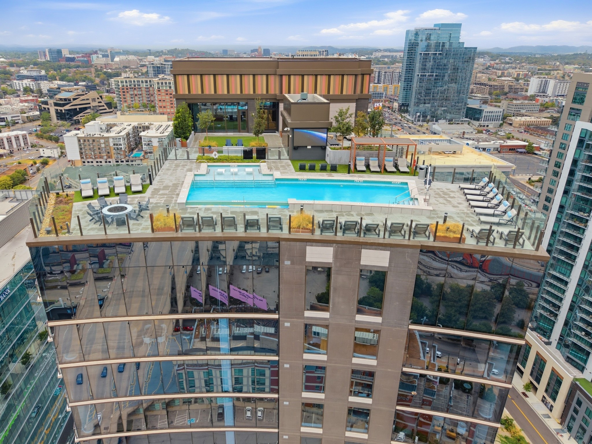 Rooftop pool and lounge deck atop a high-rise, with downtown Nashville buildings in the background.