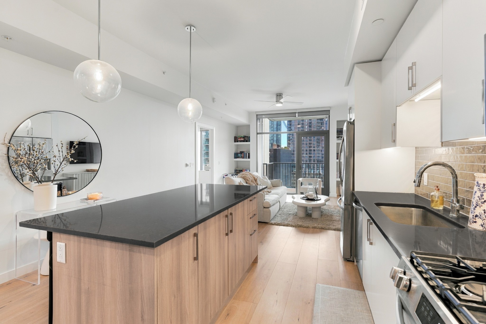 Open-plan condo kitchen with a large wood island, stainless appliances, and city views beyond the living area.