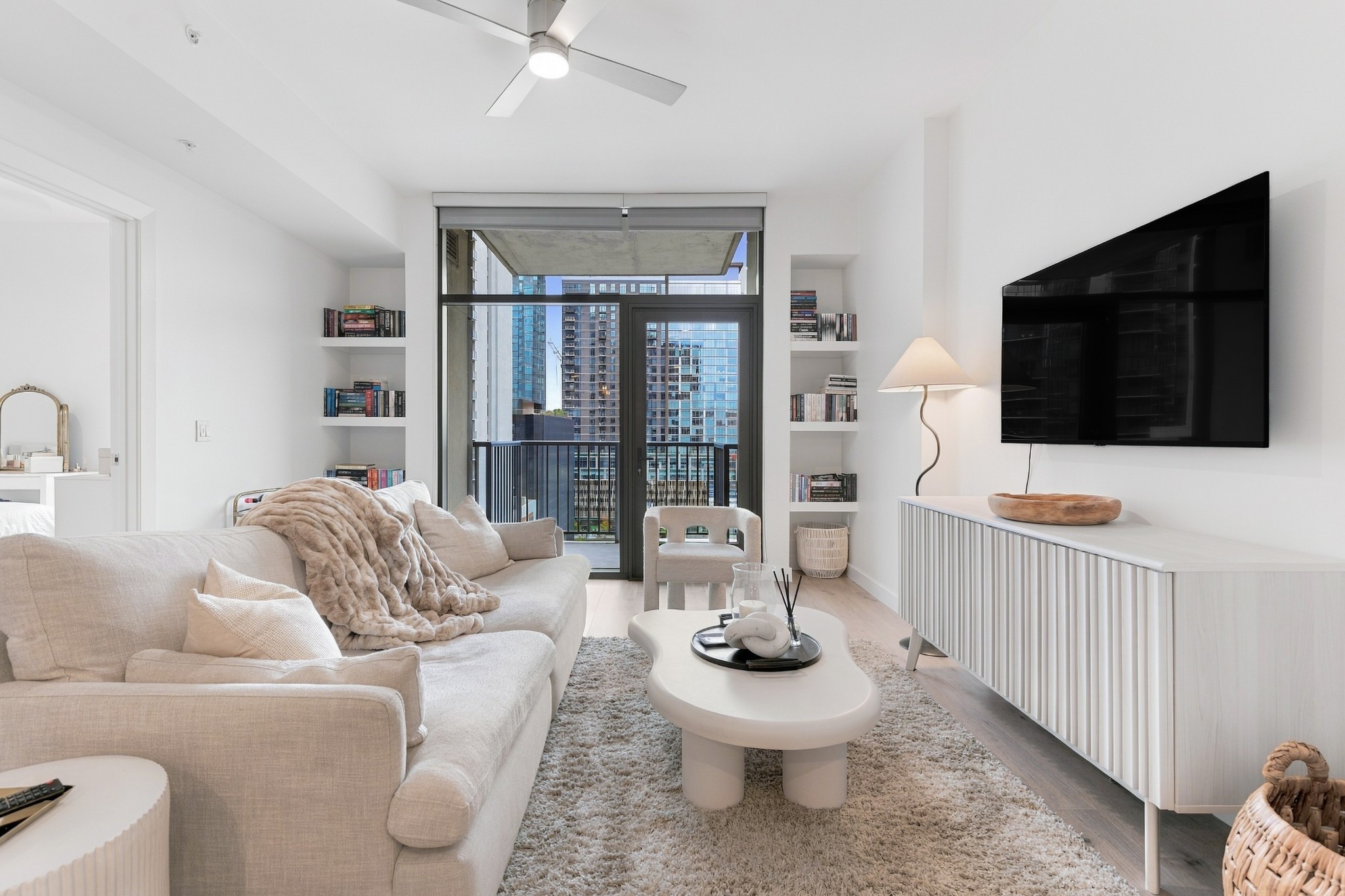 Condominium living room with a cream sectional and a balcony view of downtown buildings.