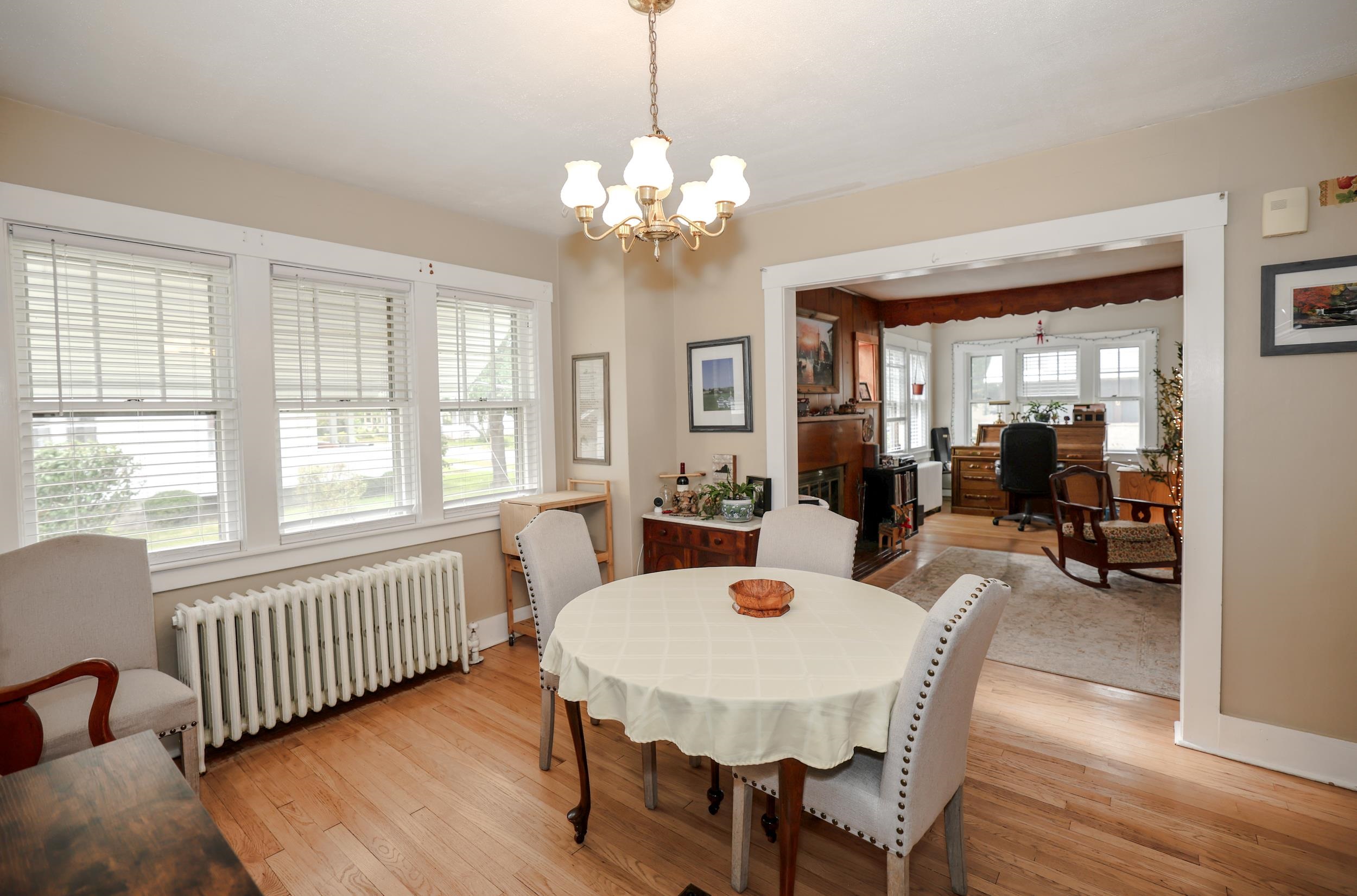 Dining room with a round table, hardwood floors, and a wide opening to an adjoining furnished room.