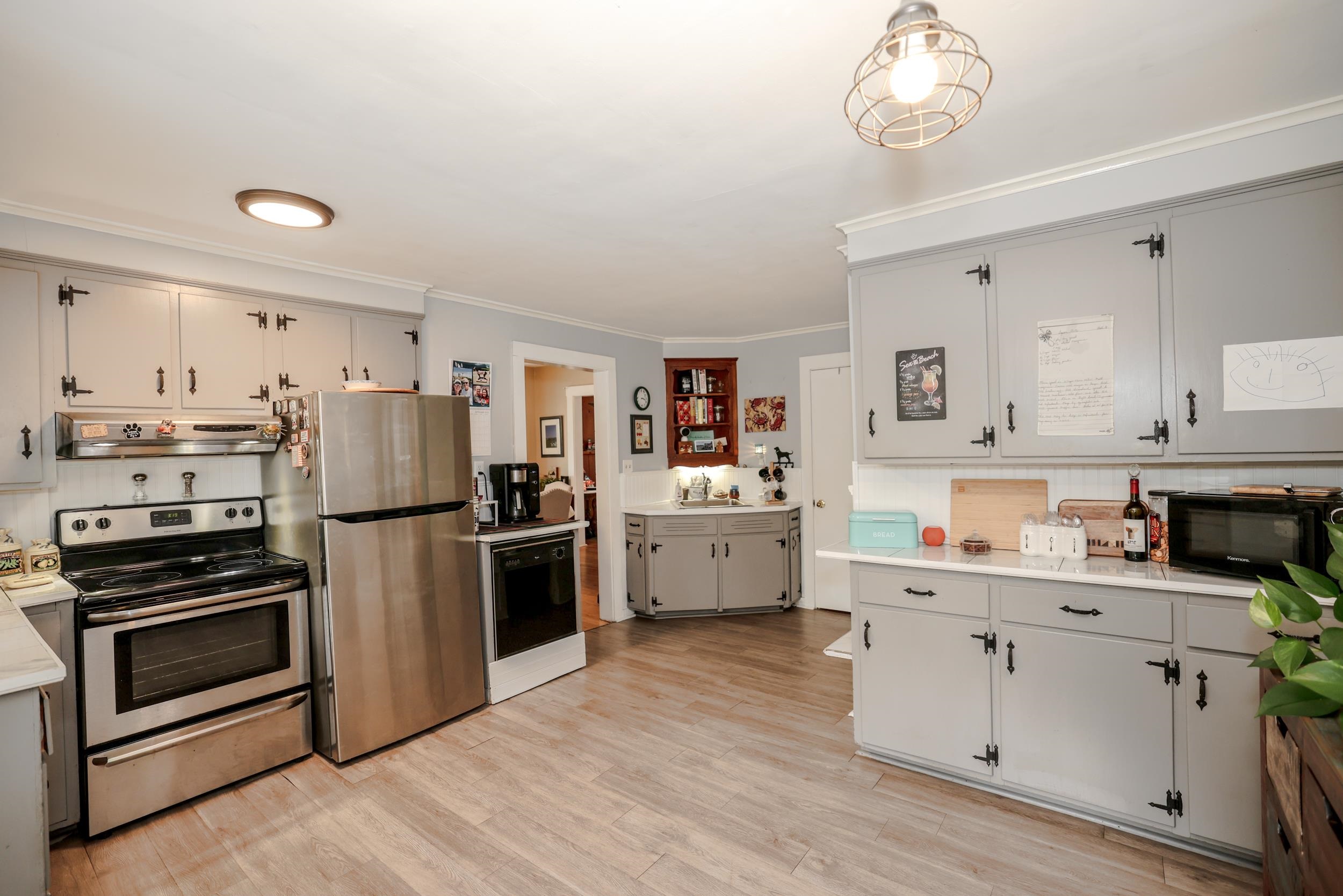 Kitchen with gray cabinets, stainless-steel appliances, and wood-look flooring.