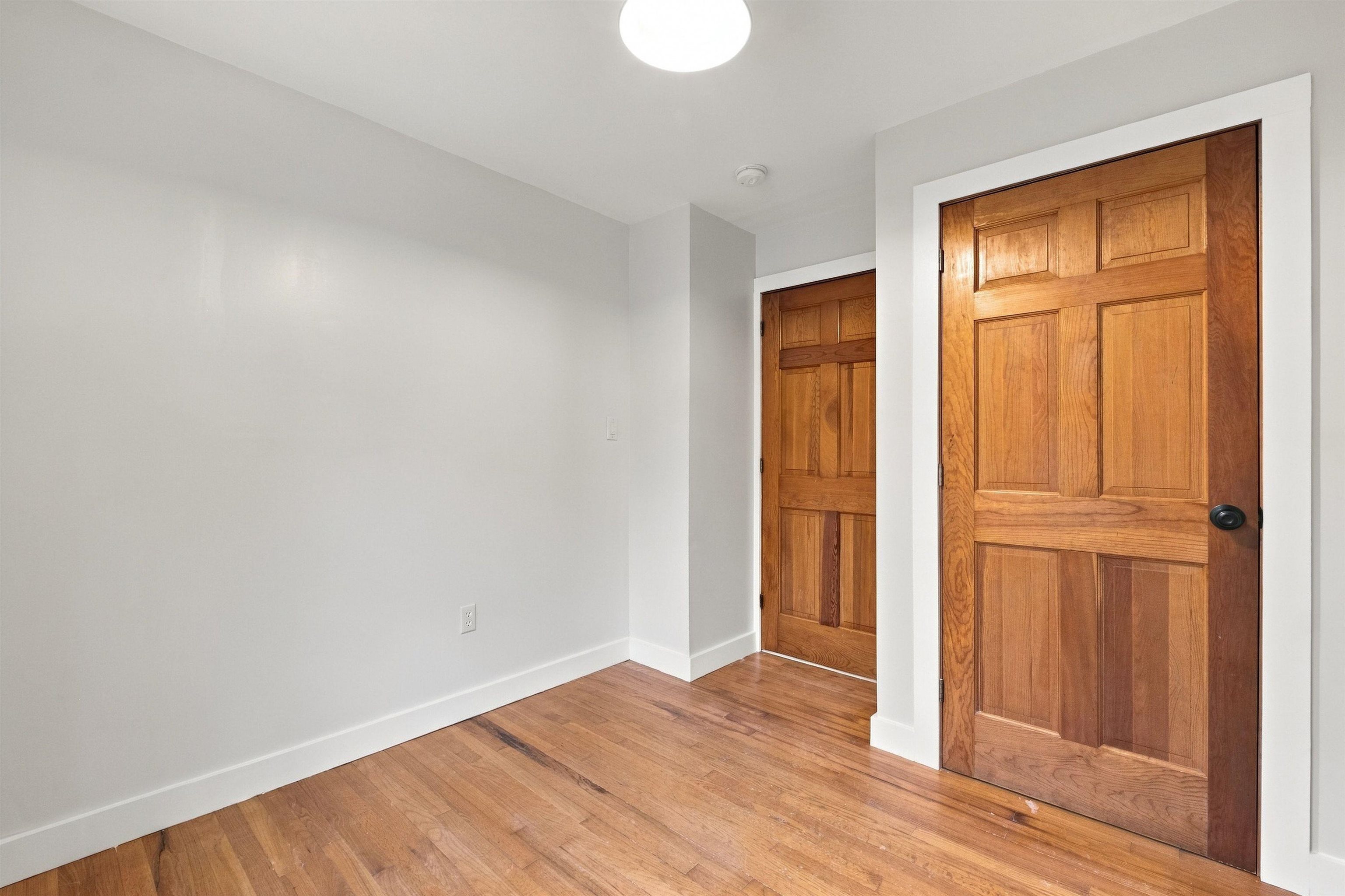 Interior hall with two paneled wooden doors and hardwood floors.