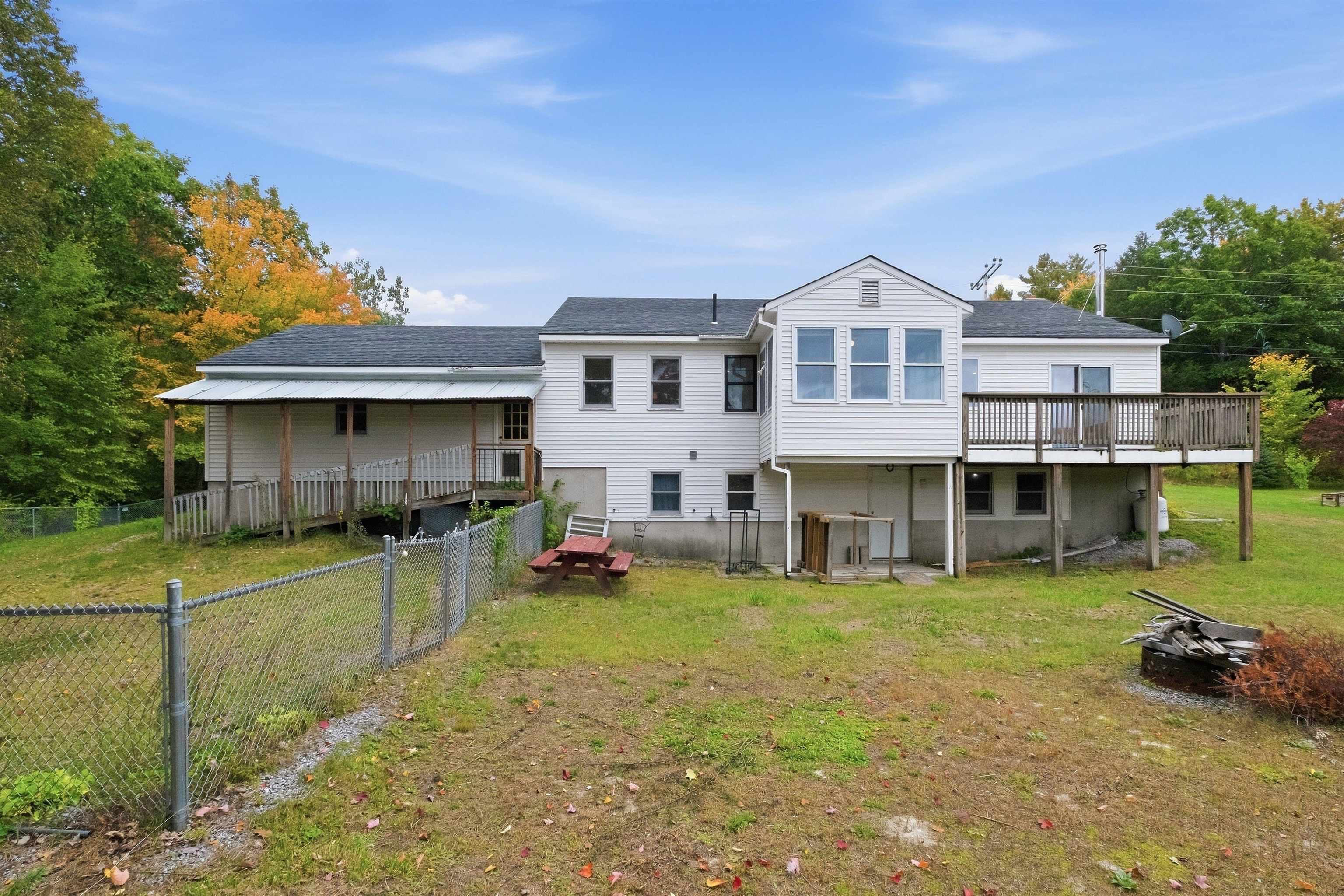 Rear of a white house with a raised deck, covered ramp, and fenced yard.