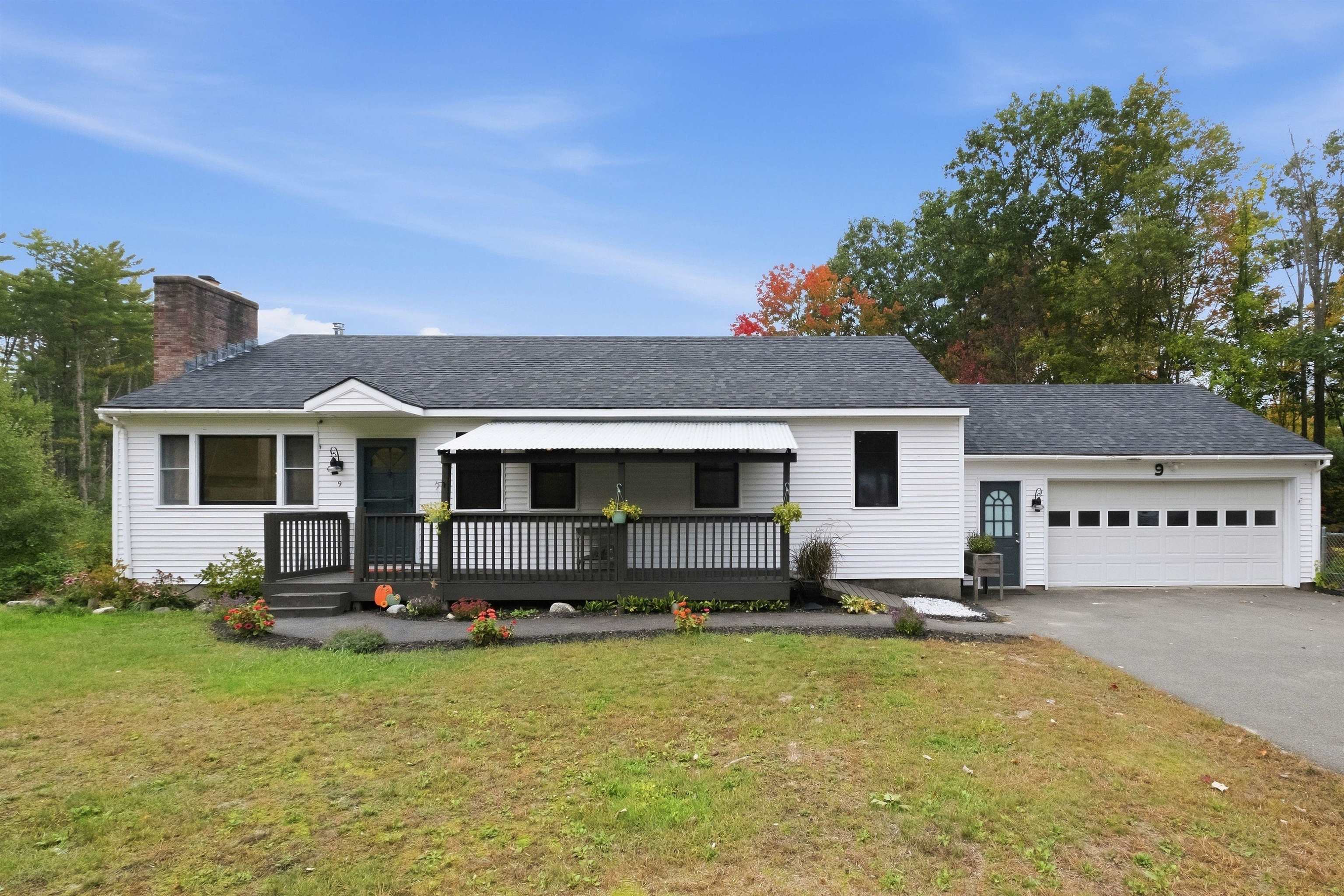 White single-story home with a covered porch, brick chimney, and attached two-car garage.