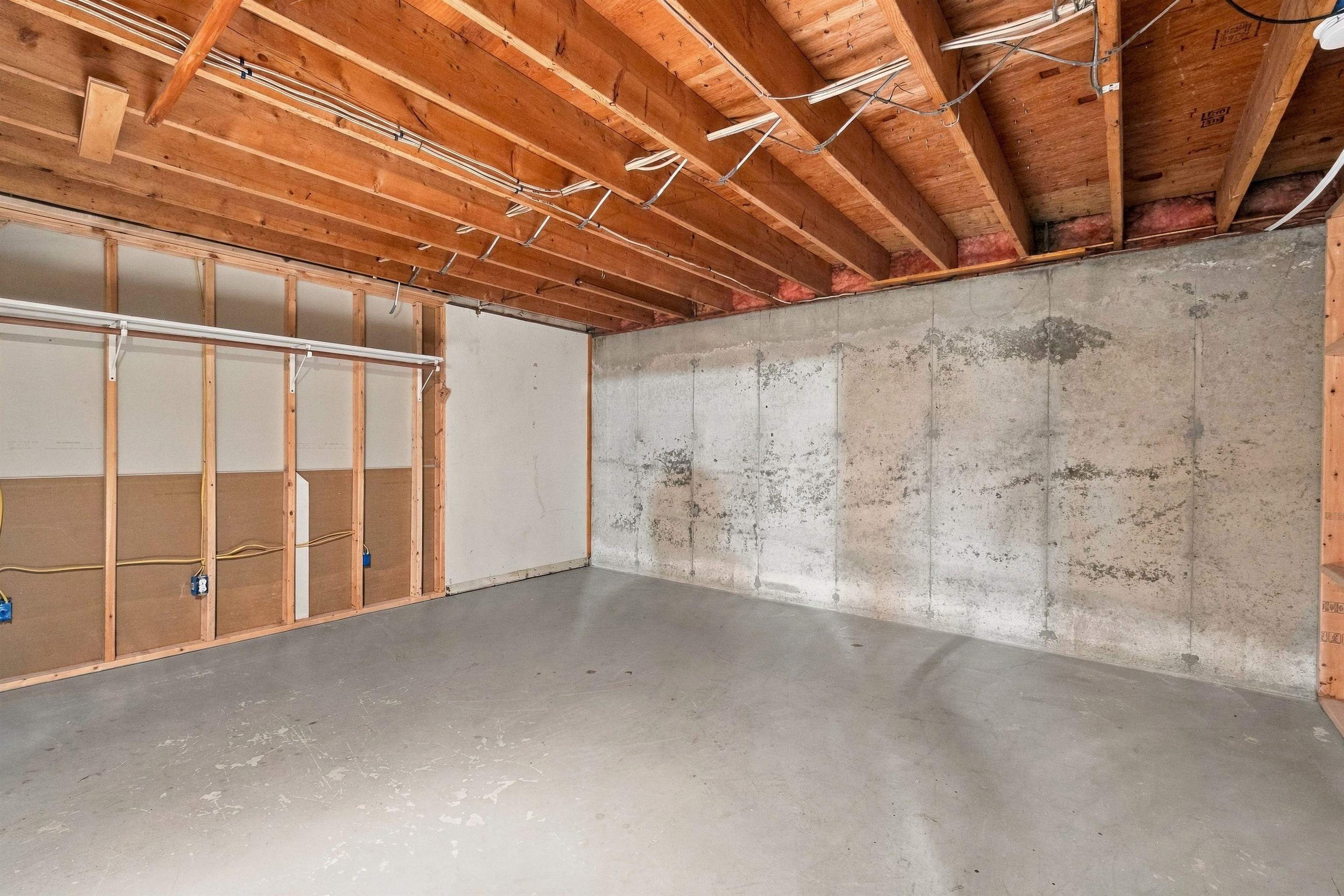 Unfinished basement with exposed ceiling joists and a broad concrete floor.