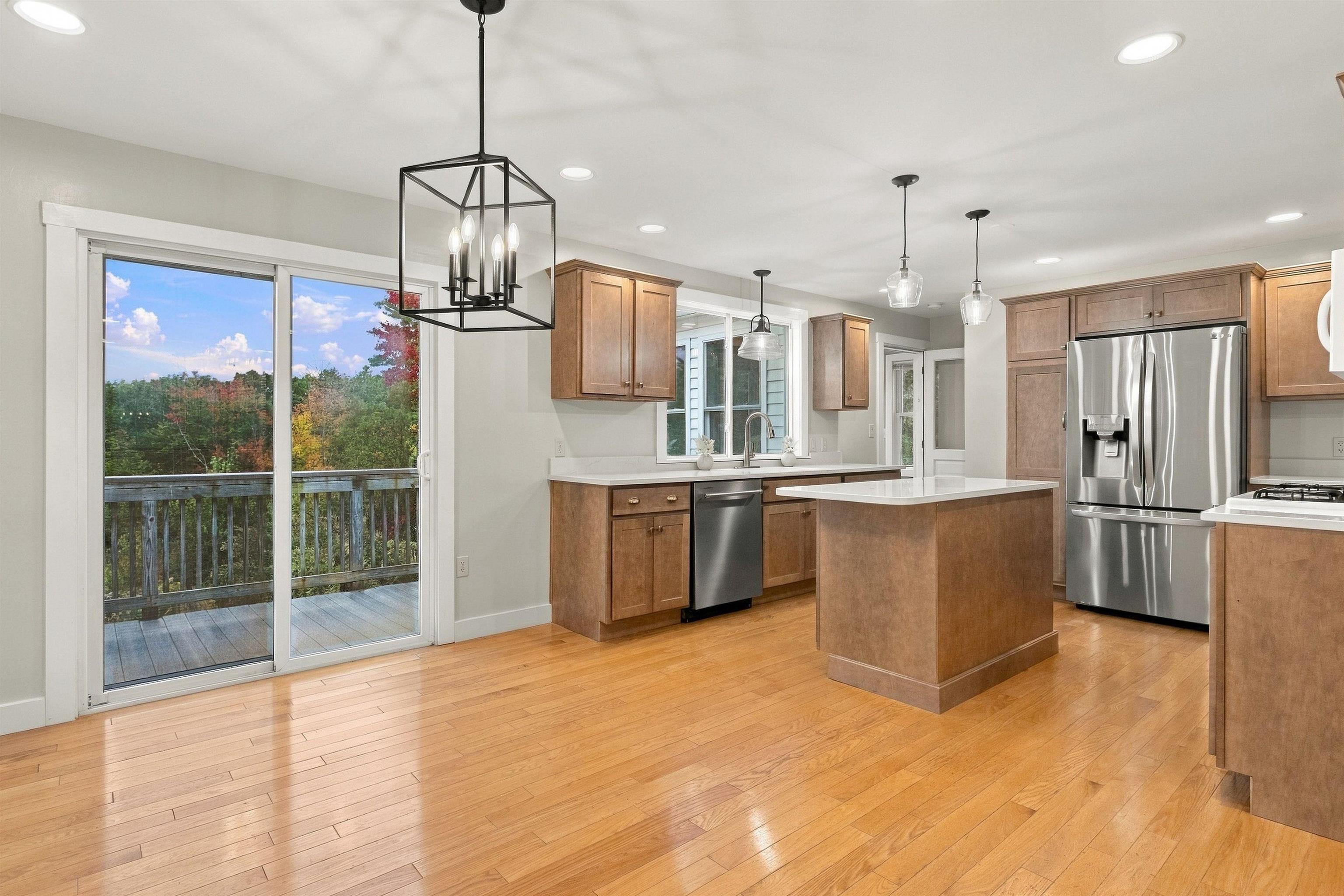 Kitchen with a central island, stainless steel appliances, and sliding doors to a wooded deck.