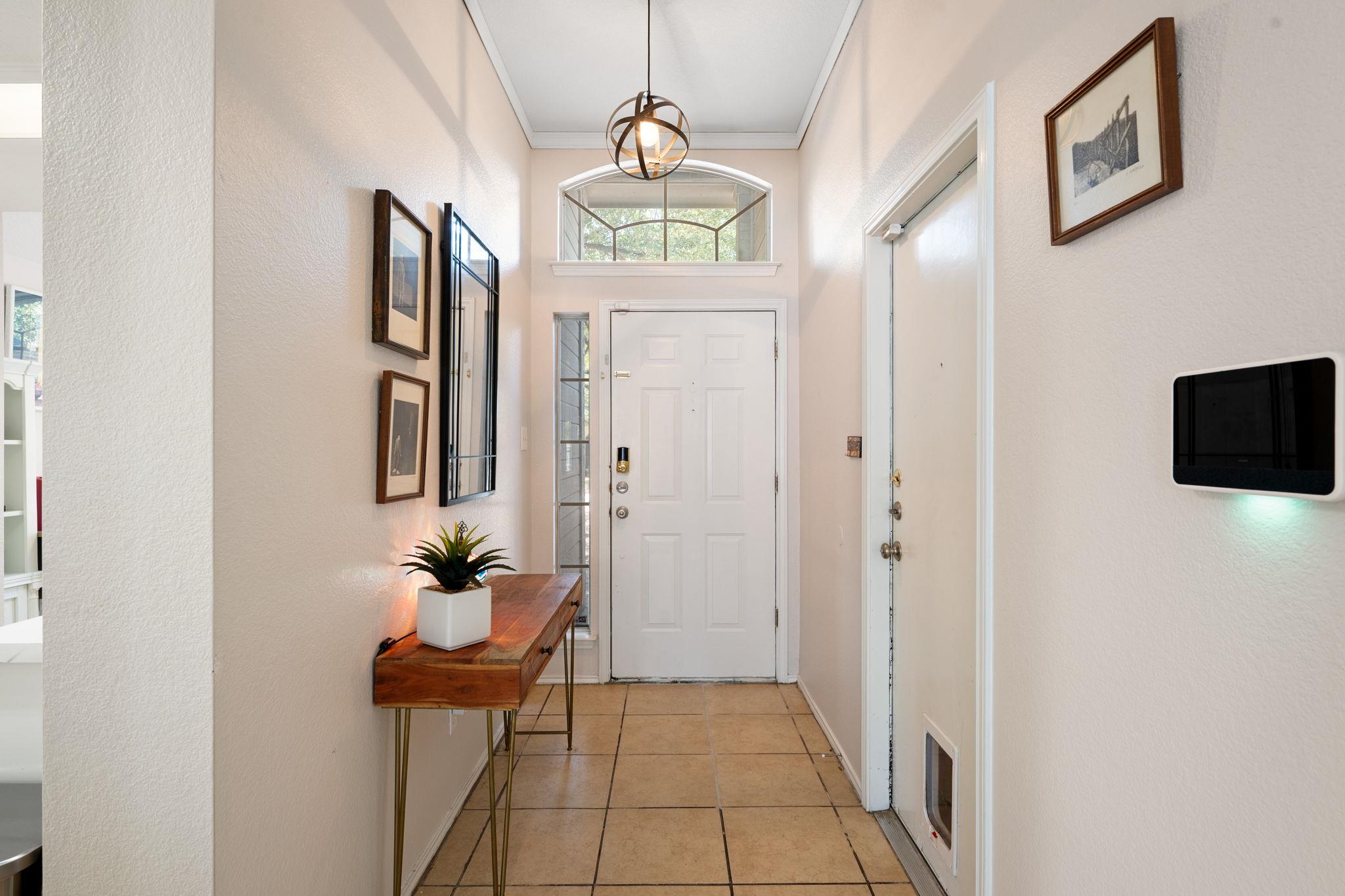 Entry foyer with a white front door, arched transom window, tiled floor, and wood console table.