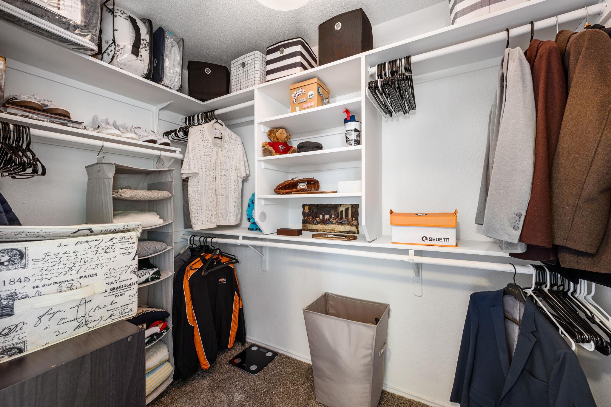 Walk-in closet with built-in shelving, hanging clothes, and organized storage.