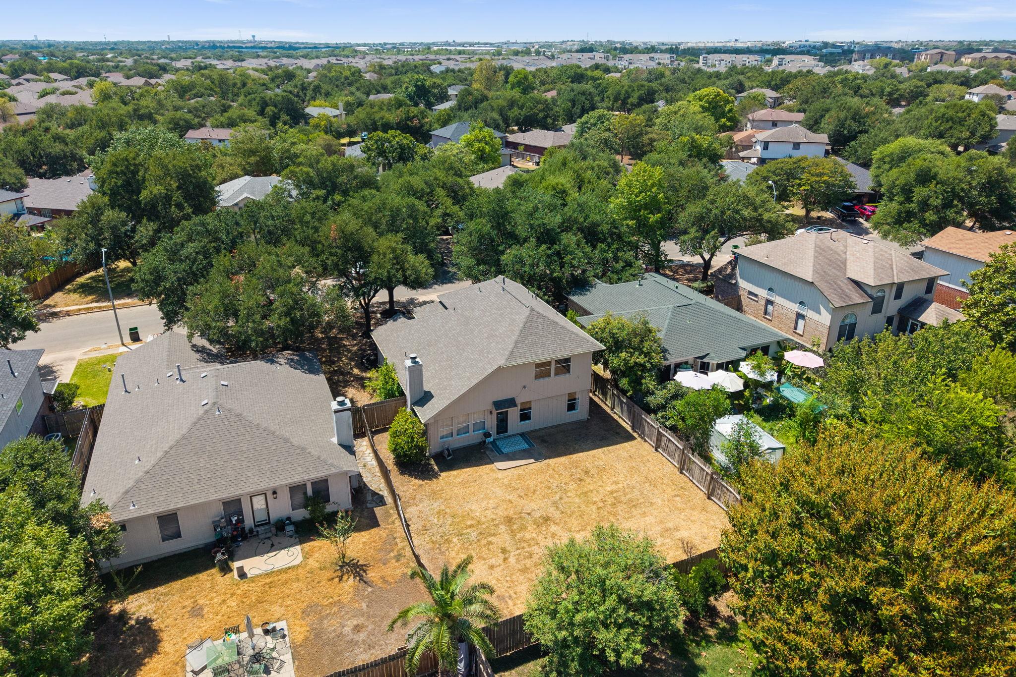 Aerial view of a two-story home with a large fenced backyard and patio dining set.