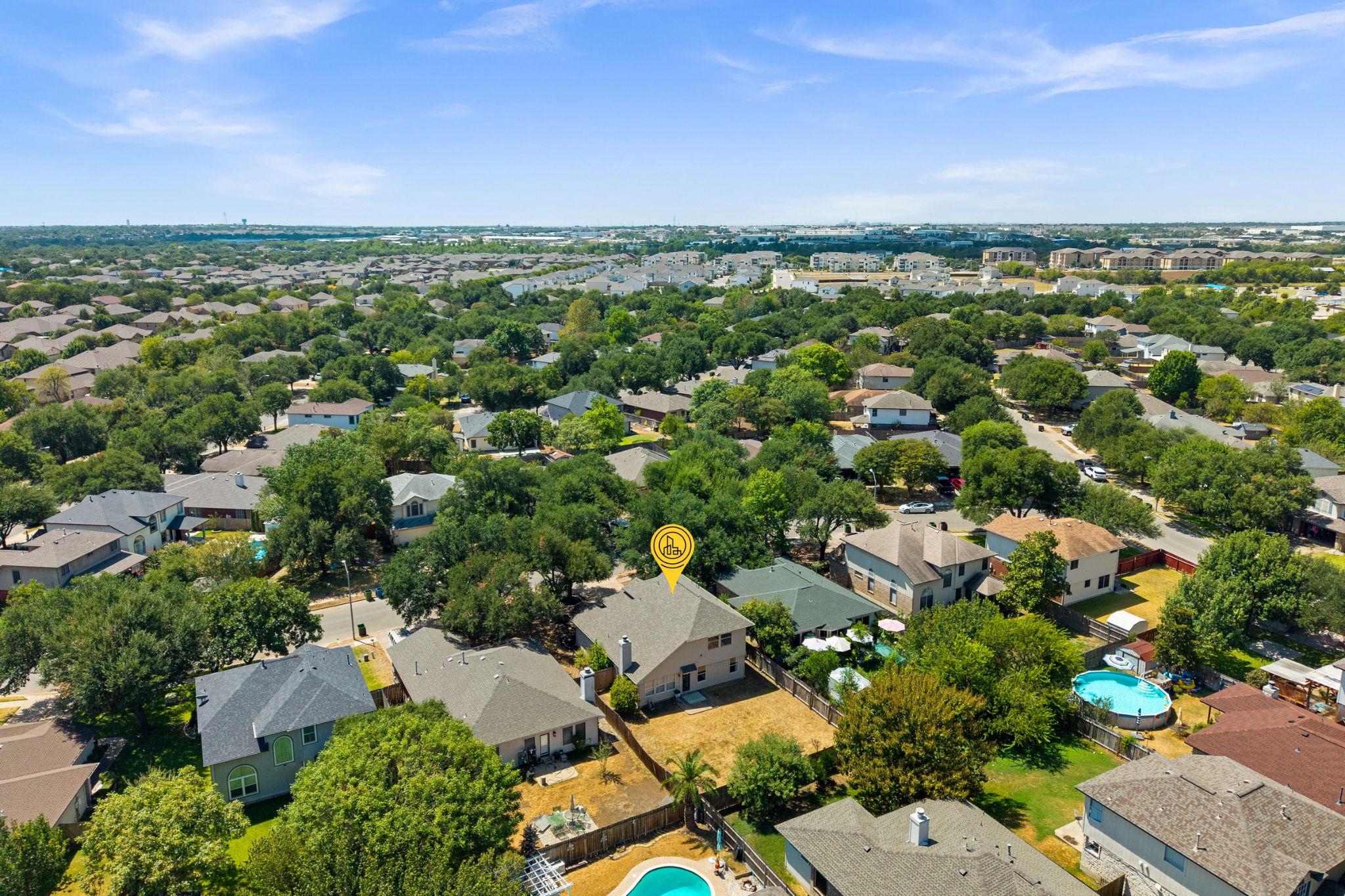Aerial view of a tree-lined Round Rock neighborhood, with the featured home marked in yellow.