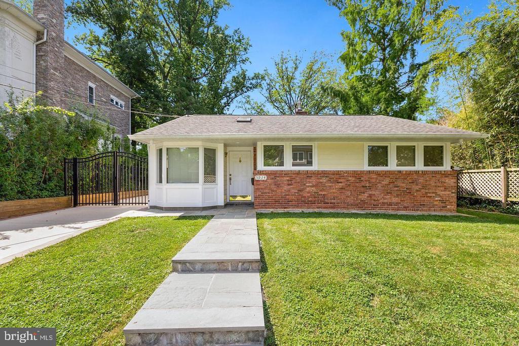 Single-story brick-and-siding house with a paved front walk, lawn, and gated driveway.
