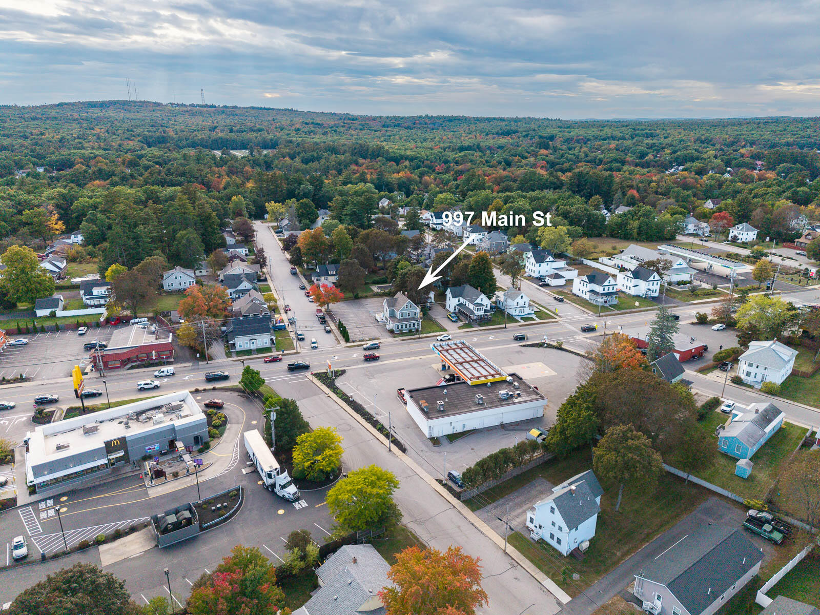 Aerial view of 997 Main Street, marked by a white arrow amid homes and businesses.