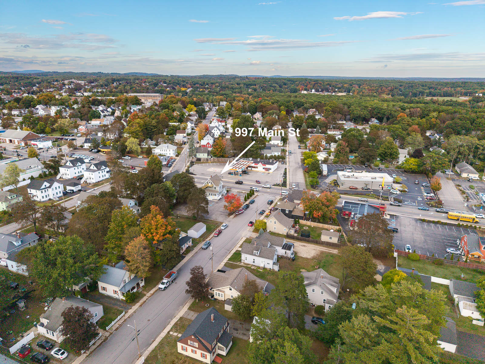 Aerial view of 997 Main Street, marked by an arrow amid nearby homes and commercial buildings.