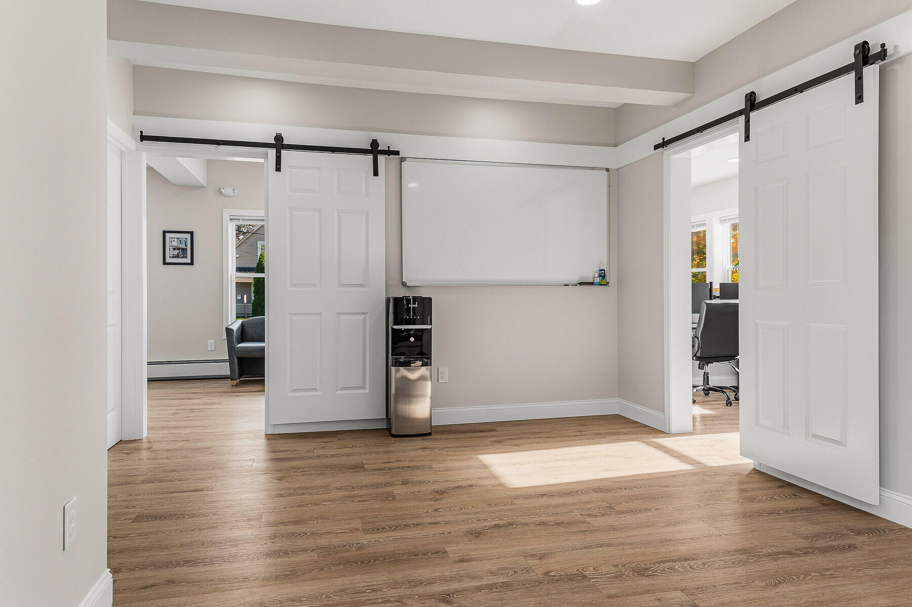 Interior room with a wall-mounted whiteboard, water cooler, and sliding barn doors opening to adjoining spaces.