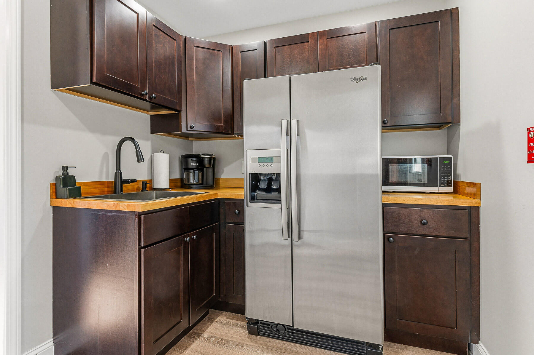 Kitchen with dark wood cabinets, wood countertops, and a stainless steel refrigerator.