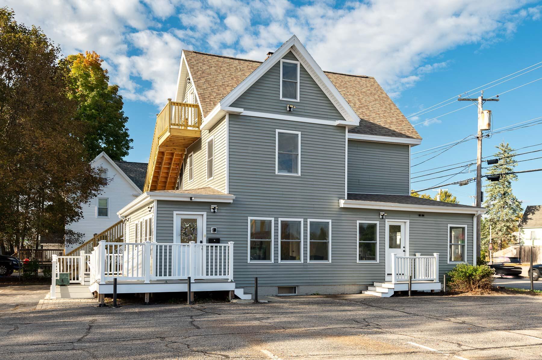 Gray multi-story house with white trim, steep gabled roof, and elevated decks and porches.