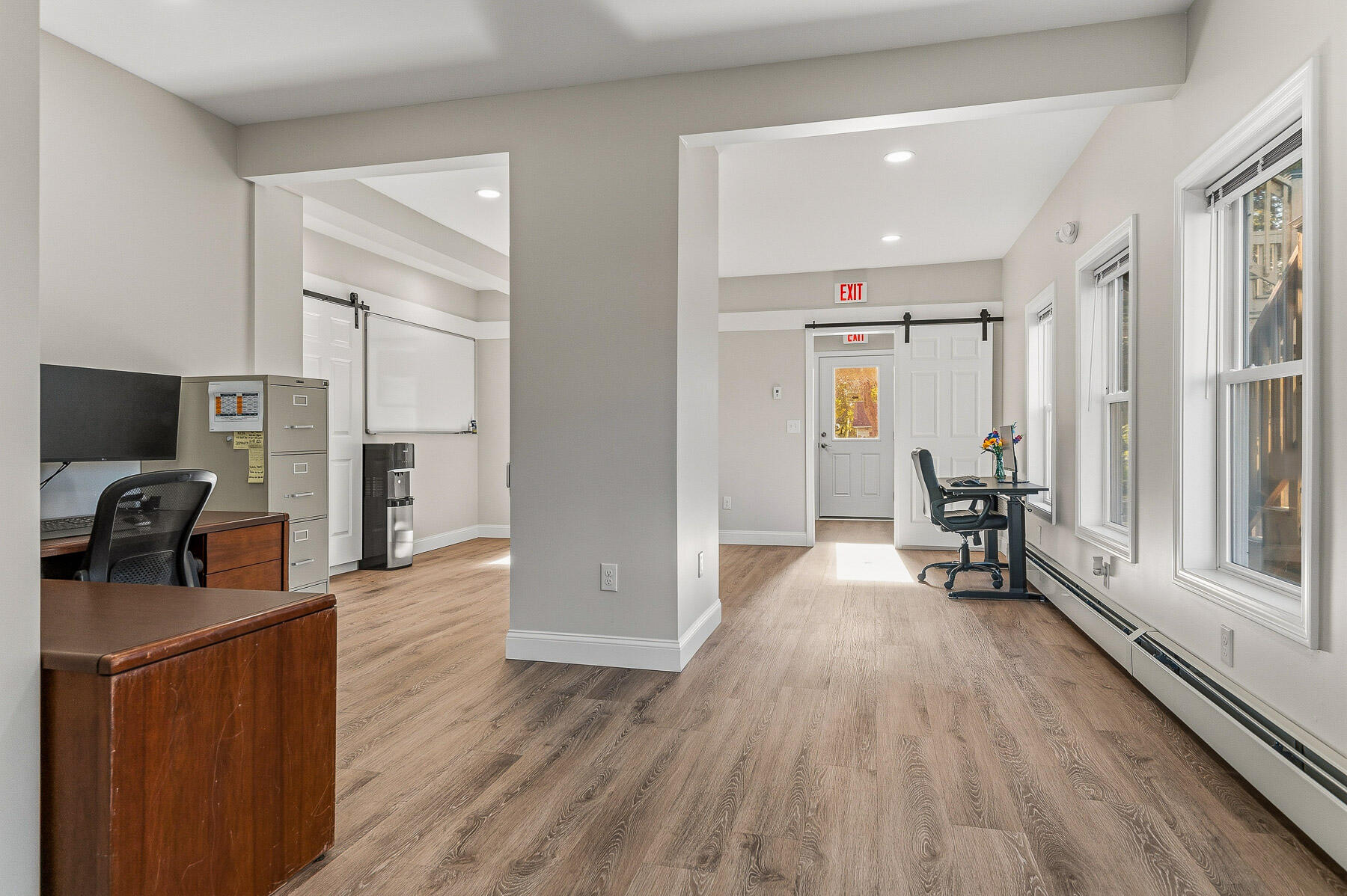 Office interior with wood-look floors, desks, and large windows.