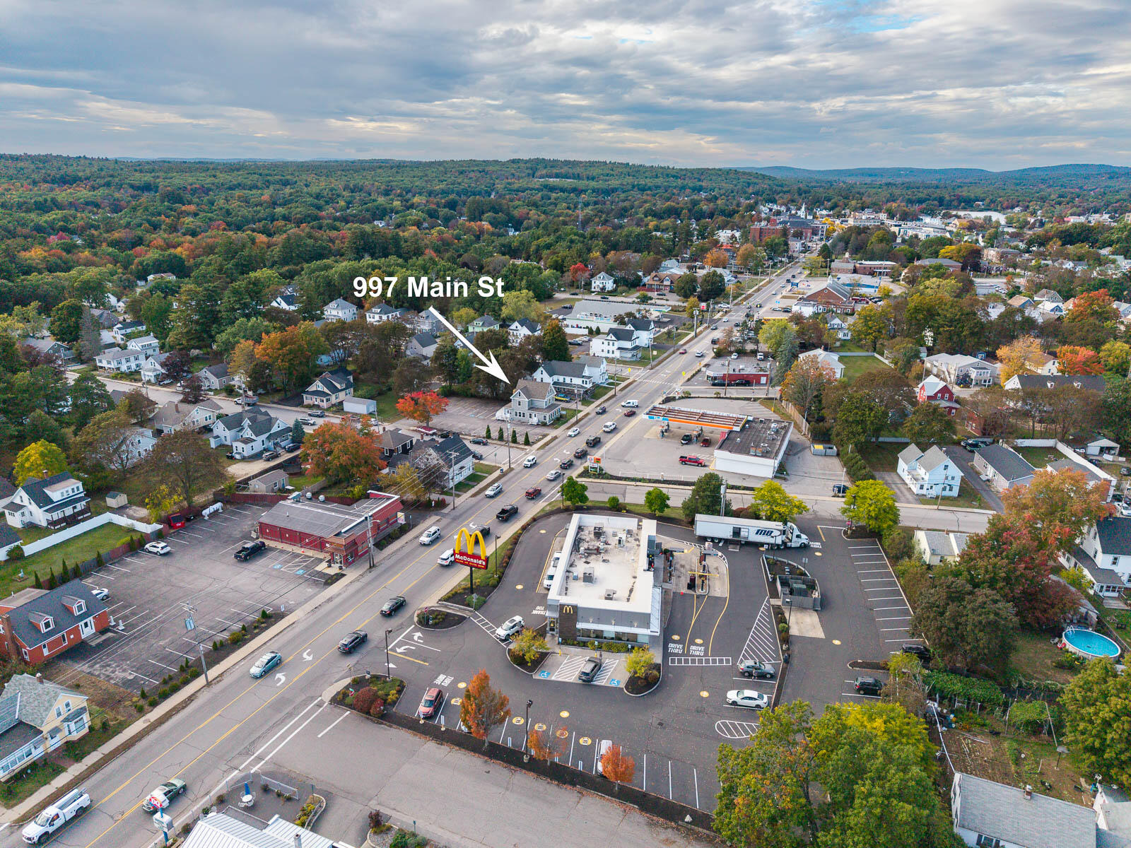 Aerial view of the Main Street property marked by an arrow, surrounded by businesses and autumn trees.