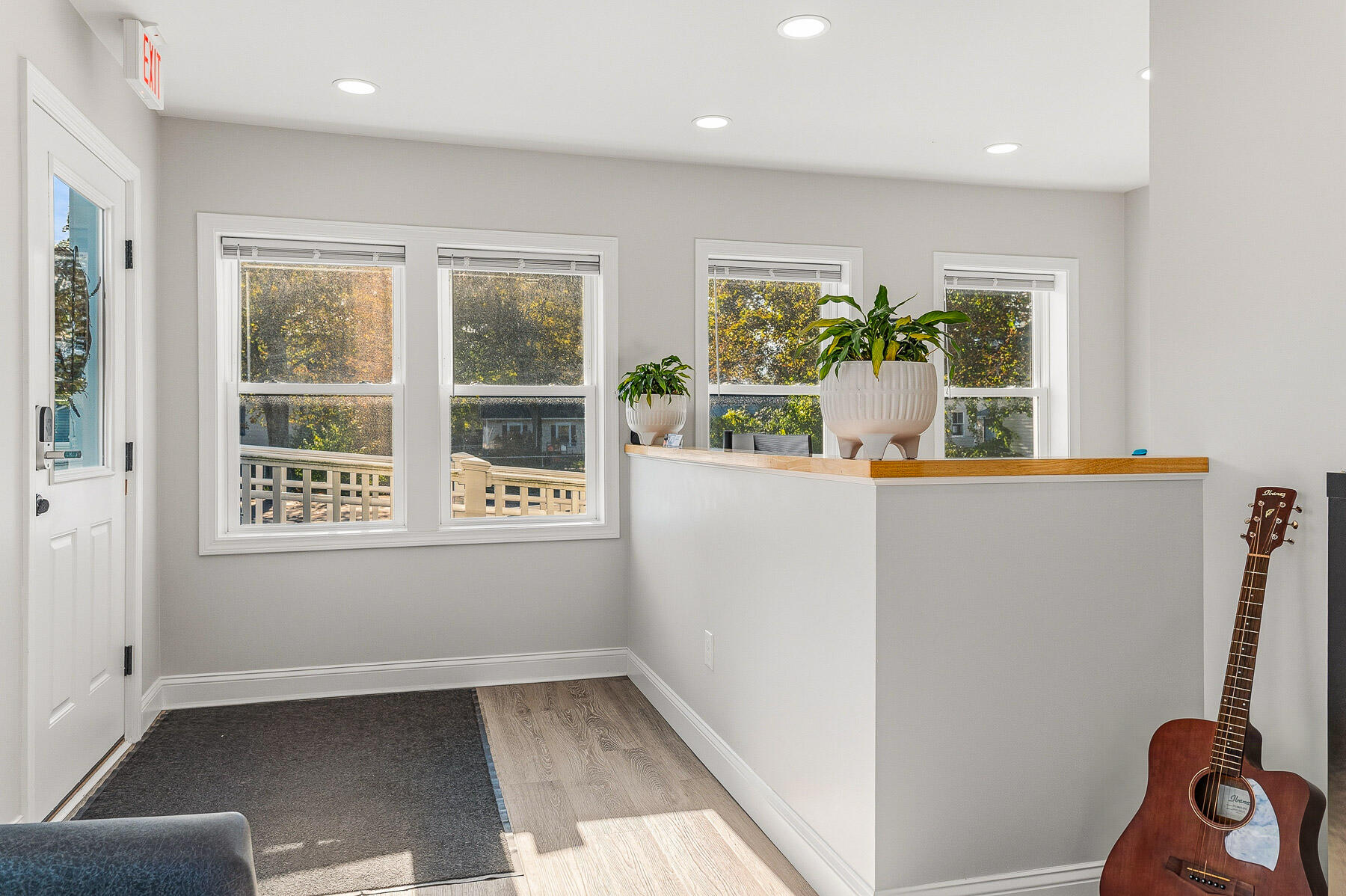Bright room with a wood-topped counter, large windows, potted plants, and an acoustic guitar.