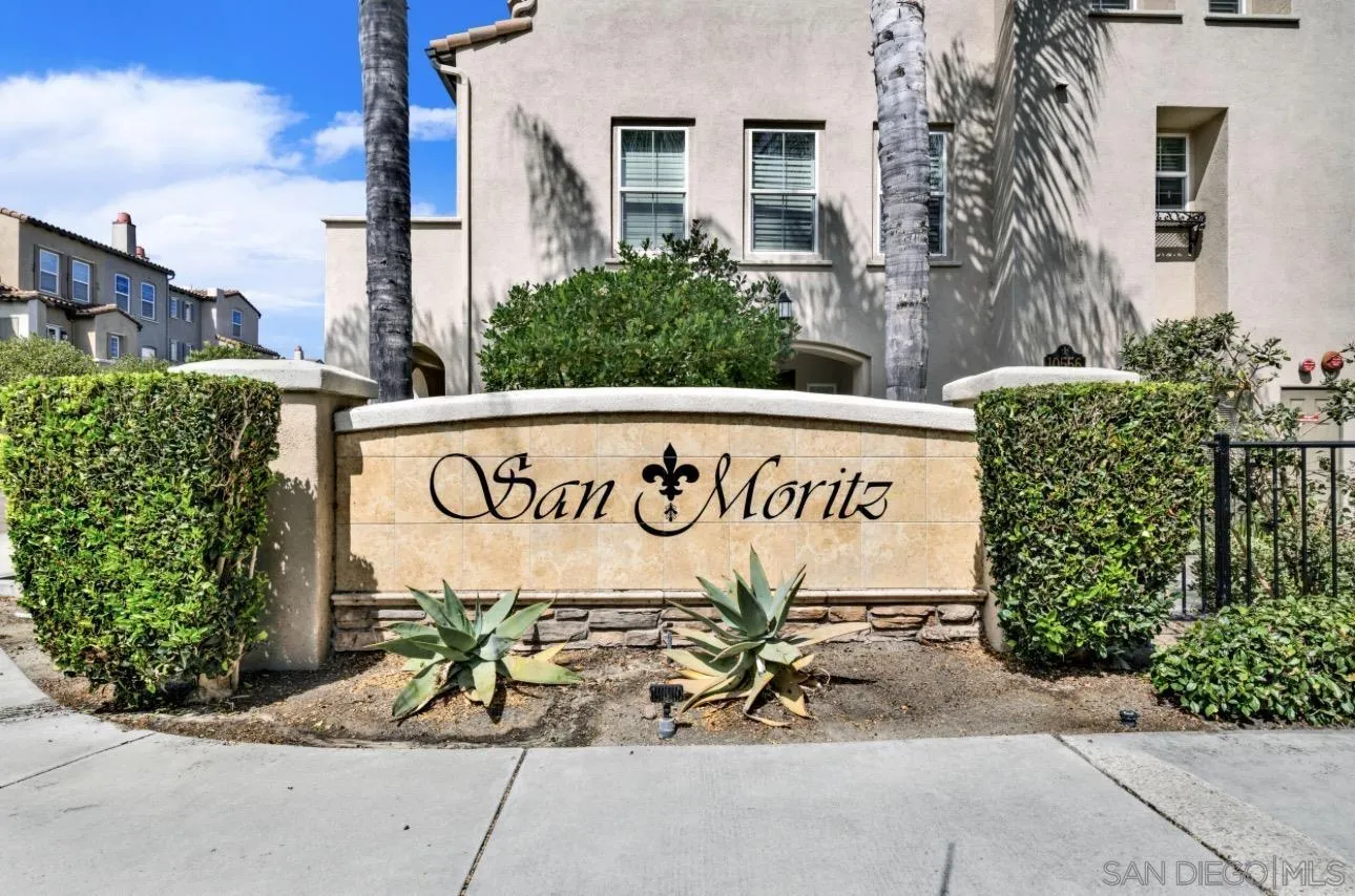 San Moritz condominium entrance sign framed by hedges, agave plants, and palm trees.