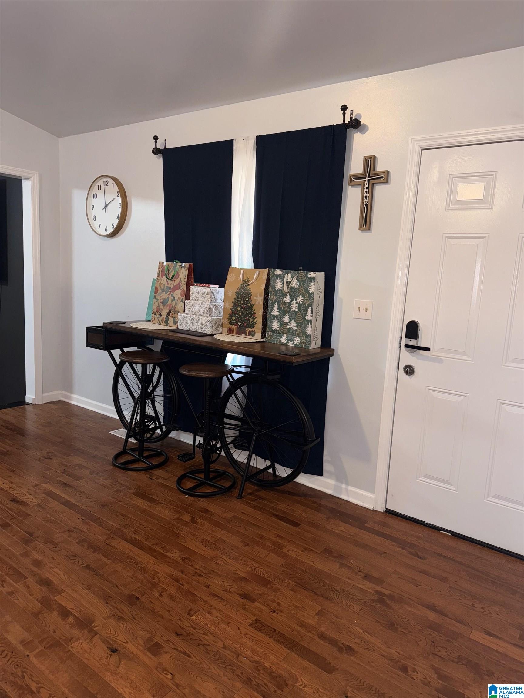 Entryway with a bicycle-style console table, navy curtains, gift bags, and hardwood floors.