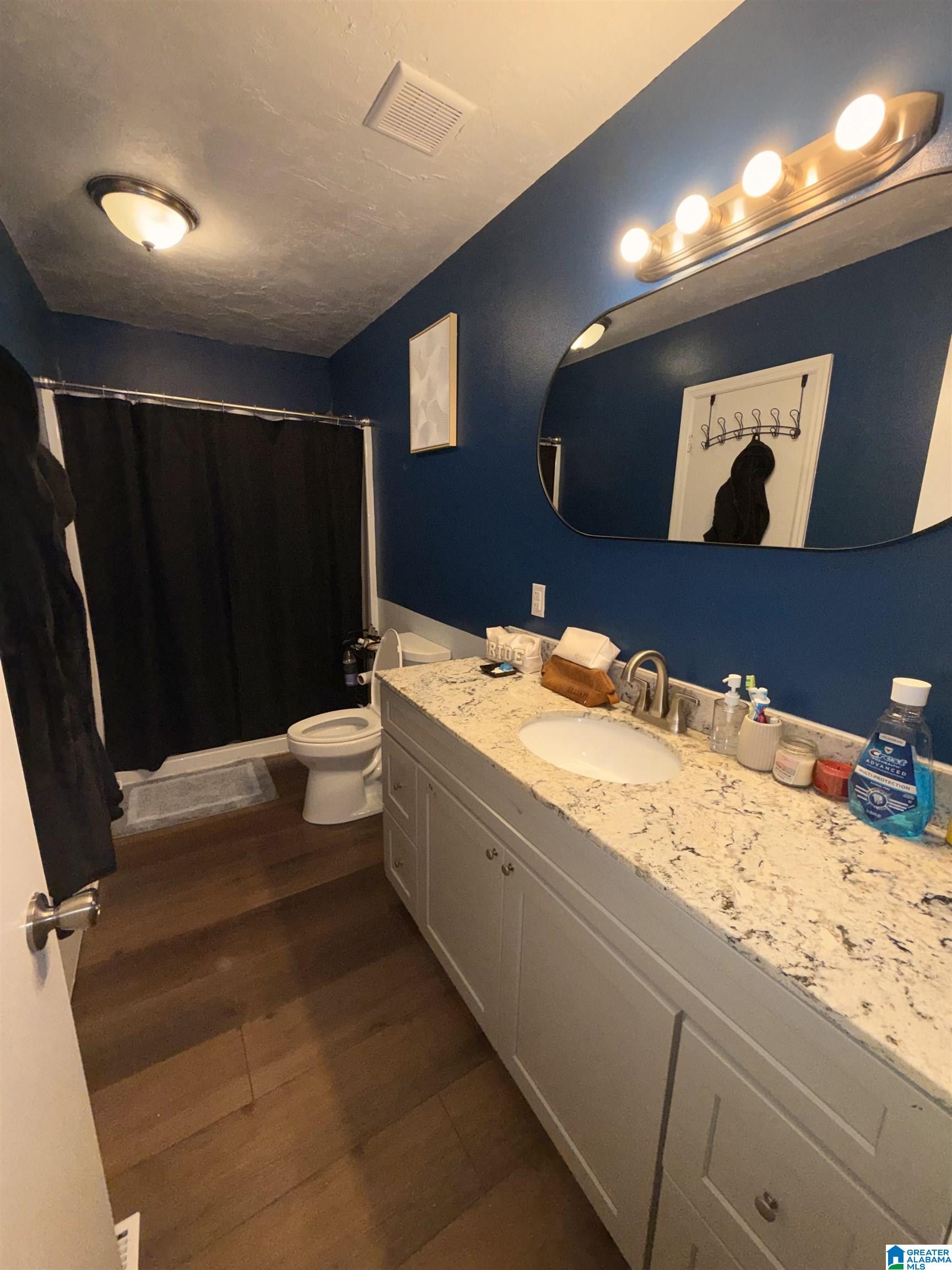 Bathroom with navy walls, a granite vanity, and a black shower curtain.
