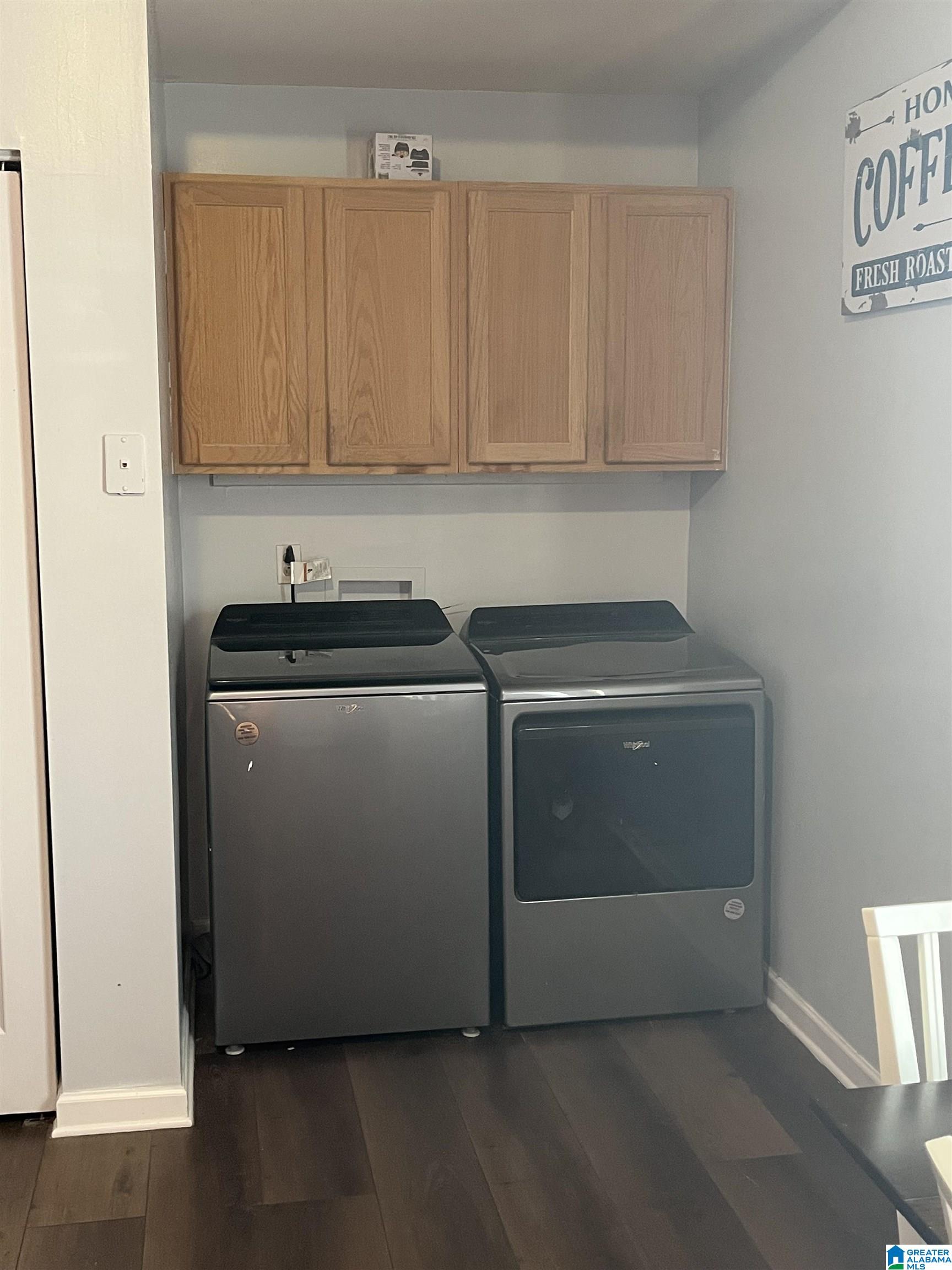 Laundry room with a washer, dryer, and four wooden wall cabinets.